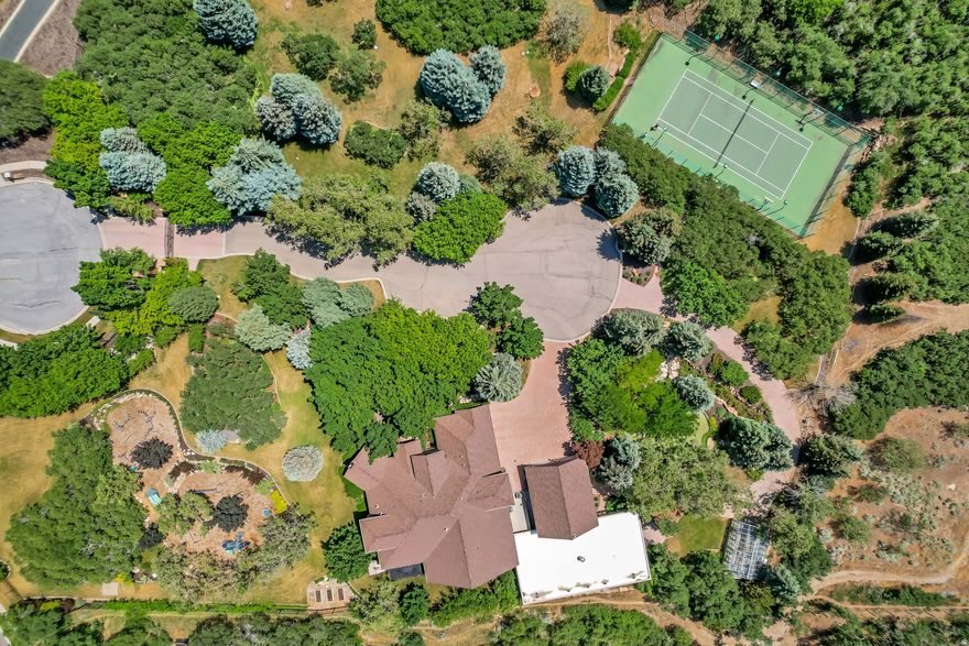 Nestled in the prestigious Holly View Acres, this 7.58-acre estate offers an extraordinary combination of luxury, privacy, and investment potential. Situated on a quiet cul-de-sac, the property is fully gated and fenced, ensuring peace of mind while embracing breathtaking 360-degree mountain views. With four total parcels, this estate presents a rare opportunity to develop, expand, or create a private retreat that backs directly up to US Forest Service Land, preserving privacy and views. The formal living room makes a dramatic first impression, featuring a vaulted ceiling, exposed wood beams, and a luxurious fireplace that serves as the focal point of the space. Expansive windows allow for abundant natural light, highlighting the warmth and elegance of the room. Just beyond, the kitchen is designed for both functionality and entertaining, featuring double wall ovens, a built-in countertop gas range, and a semi-formal dining space. A formal dining room sits adjacent, offering the perfect setting for hosting and entertaining. At the heart of the home, the Great Room boasts a soaring vaulted ceiling, and seamlessly connects to the balcony deck, creating an effortless indoor-outdoor living experience. Enjoy single level living with the Primary Suite on the Main Level, providing a luxurious retreat complete with an oversized shower, jetted soaker tub, and a connecting den with built-in hardwood shelving and workspace for work or relaxation. With 7 bedrooms and 6.5 bathrooms, this home offers abundant space for family and guests alike. Laundry rooms on every level add convenience to daily living, ensuring ease and efficiency throughout the home. The walkout basement is designed for versatility, featuring a full kitchen, designated dining area, and family room with its own separate entrance, making it an ideal mother-in-law apartment, guest suite, or private retreat. The basement is also host to a theater room with stadium seating, making family nights & entertainment at home a breeze. A dedicated wellness and recreation prep area within the basement includes a separate bathroom, shower, Finlandia Sauna, and a Suitmate Swimsuit Water Extractor, ensuring a spa-like retreat after a swim or workout. The indoor heated pool and spa is housed separately from the main residence yet remains easily accessible through the basement entrance. Designed for year- round enjoyment, this space features sliding glass doors around the structure, allowing for an open-air experience when the weather is nice. The surrounding area provides ample room for games, activities, and hosting, making it an entertainer's dream. Stepping outside, the backyard is a paradise for recreation and relaxation, featuring play gyms and equipment for kids, a putting green, a tennis court, and a large greenhouse for homesteading. Whether enjoying outdoor activities or simply taking in the breathtaking scenery, this estate offers an unmatched setting for enjoying the great outdoors. With a stunning paver driveway and oversized 3-car garage with plenty of room for vehicles, toys, and storage, this Estate truly is the perfect blend of practicality and luxury. With its prime location, expansive acreage, and endless amenities, this estate is a rare find in Alpine. Don't miss the opportunity to experience this one-of-a-kind property. Schedule a private tour today! Buyer/Buyer's Agent to verify all.