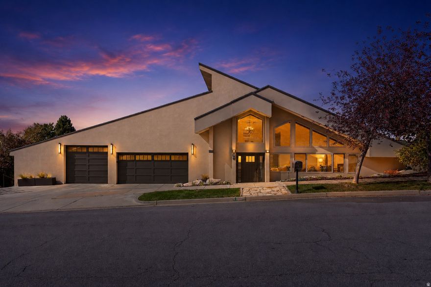 Perched high in the prestigious Moss Hill neighborhood, this 7,073 sq ft estate was designed to capture light, space, and sweeping Great Salt Lake views.  The soaring Grand Room features vaulted ceilings with exposed beams and dramatic walls of windows, including six south-facing windows engineered to flood the home with natural light year-round. Its signature "Moonlight Architecture" even frames the full moon perfectly from the kitchen island.  The remodeled chef's kitchen offers quartz countertops, custom cabinetry, double wall ovens, a gas cooktop, and an oversized island that flows seamlessly into the great room and dining space. Step onto the expansive deck to take in unforgettable city and sunset views. The primary suite is a private retreat with balcony access and a spa-inspired ensuite featuring dual vanities, a soaking tub, and a tiled walk-in shower.  The walkout lower level-"The Terrace Villa"-completely redefines basement living with rare 10-foot ceilings, full daylight access, zero window wells, and unobstructed sunset views from every room. Designed for flexibility, it can function as a luxury rental, private guest quarters, or a multigenerational suite with verified income potential of approximately $2,100/month.  Outside, enjoy a rare sprawling flat lawn-almost unheard of on the Bench-plus a $50,000 industrial epoxy showroom garage with room for 3 vehicles, ATVs, storage, and workshop space. With 5 bedrooms, 5 bathrooms, and over 7,000 square feet of thoughtfully updated living space, this estate combines architectural design, income versatility, and luxury living.  Attractive financing options under 6% and potential seller-paid rate buydown incentives may be available for qualified offers  Call Sally at 949-274-5866 to schedule a private showing.