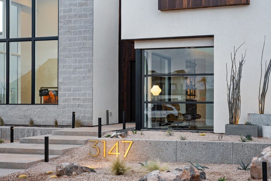 Desert luxury meets effortless living in this striking custom home, where mid-century design and Scandinavian warmth come together in perfect balance. Tucked at the end of a quiet cul-de-sac on a private .35-acre lot, this former Parade Home backs to a serene hillside and is just moments from Copper Rock Golf Course and Sand Hollow reservoir, offering the best of Southern Utah's outdoor lifestyle right at your doorstep. Inside, walls of glass and soaring 22' ceilings create a light-filled great room designed for gathering. The kitchen is both functional and beautiful, featuring warm walnut accents, premium appliances, and a custom banquette perfect for slow mornings or hosting friends. The layout flows effortlessly from intimate spaces to entertaining areas, including a full bar, theater, and music room. The upper level is thoughtfully designed for both privacy and connection, highlighted by a tranquil primary suite with a Japanese soaking tub, and private deck...your own personal retreat. Outside, the experience continues with resort-style living: a custom pool with integrated spa, fire feature, in-water seating, and a climbing wall, plus a rooftop deck ideal for sunset views. Whether you're entertaining or unwinding, every space is designed to elevate everyday living. A private casita complete with its own kitchenette offers flexibility for guests or extended stays, while an expansive garage with 4 RV bays and curated designer finishes throughout complete this exceptional desert escape.