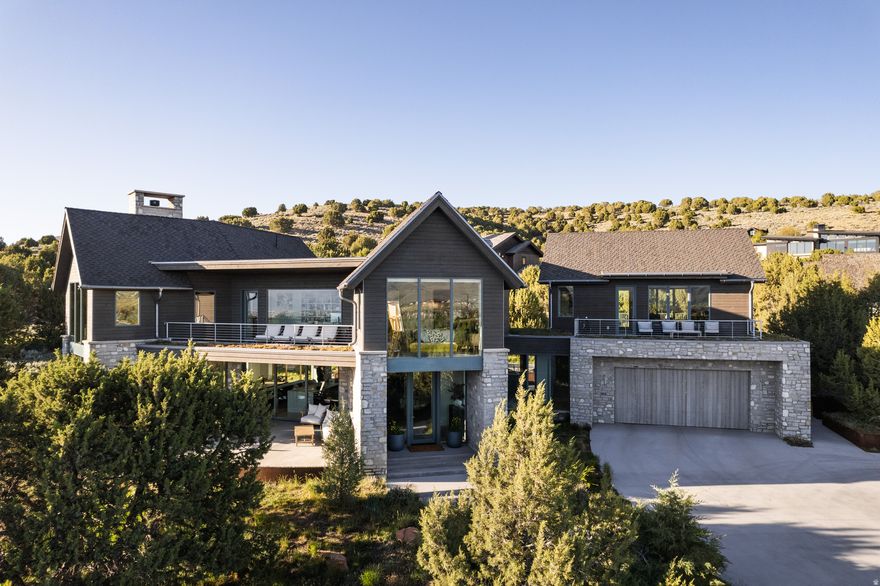 Perfectly positioned to take advantage of sunlight and stunning views at every turn, this incredible custom-built, mountain-modern residence offers a rare opportunity to live in the sort of property that exists in harmony with the natural landscape. Large 150-year-old junipers dot the sizable lot, offering privacy and connection to the outdoors from every angle, and the wild flowers that bloom in early summer make the setting unforgettable. Constructed with passive solar principles, every room plays intentionally with light and shadow, artfully providing quiet places from which to take in the surrounding vistas. With five patios-each framed with corten steel planters and rooftop gardens-there is always a spot in which to enjoy the high desert landscape, no matter the season or time of day. Consider the early light glow on Timpanogos from the kitchen as you sip coffee and evening happy hours overlooking Deer Creek reservoir. Inside, no detail big or small has been overlooked: conveniences and comforts abound in the form of a filtered water station, mudroom with built-in dog kennel area, floor-to-ceiling Pella architectural windows, vaulted ceilings, a tiered great room, oversized sliders, a whole-home audio system, Control 4 panel for draperies and lights, and so much more. Cooks and design aficionados alike will swoon over the kitchen. Whether you're cooking for one or for twenty, you'll do so in comfort and style, thanks to a large, honed quartzite island, Wolf and Subzero appliances (including a state-of-the-art recessed hood), and a Scotsman ice maker. A large dining area connects seamlessly to a comfortable lounge area framed by more of the aforementioned breathtaking views, and a cozy gas fireplace (that can also burn wood, if desired). On heading upstairs, a custom cold-rolled steel stringer with organic modern design brings you to three generously sized bedrooms, a pass-through library, and some additional deck space. The luxurious bathrooms feature stunning tile, terrazzo floors, and a primary bath steam shower. And for those who enjoy movie and game nights, a large family room with its own en-suite bathroom and two private patios can flex as a guest space (sleek Murphy bed included). The garage is a showpiece in and of itself: the space that is heated, cooled, and EV-enabled, but it's also complete with a dog wash, ski room, workbench, hot and cold hose bibs, full sound system, and an additional storage room and mechanical area below. The Red Ledges community is located just 20 minutes from Park City, which bodes well for those inclined to a full outdoor life. Deer Valley Resort's world-class skiing (and accompanying lodge and club memberships) is just a 15-minute drive. Moreover, this home offers a Lifestyle Membership with access to the Swim & Fitness Club, The Cliff Drysdale Tennis School, and an Equestrian program. You'll find no compromise here-just perfectly executed form and function accounted for at every turn. Properties of this caliber, and in this setting, do not come available often.  Square footage figures are provided as a courtesy estimate only.  Buyer to verify all.