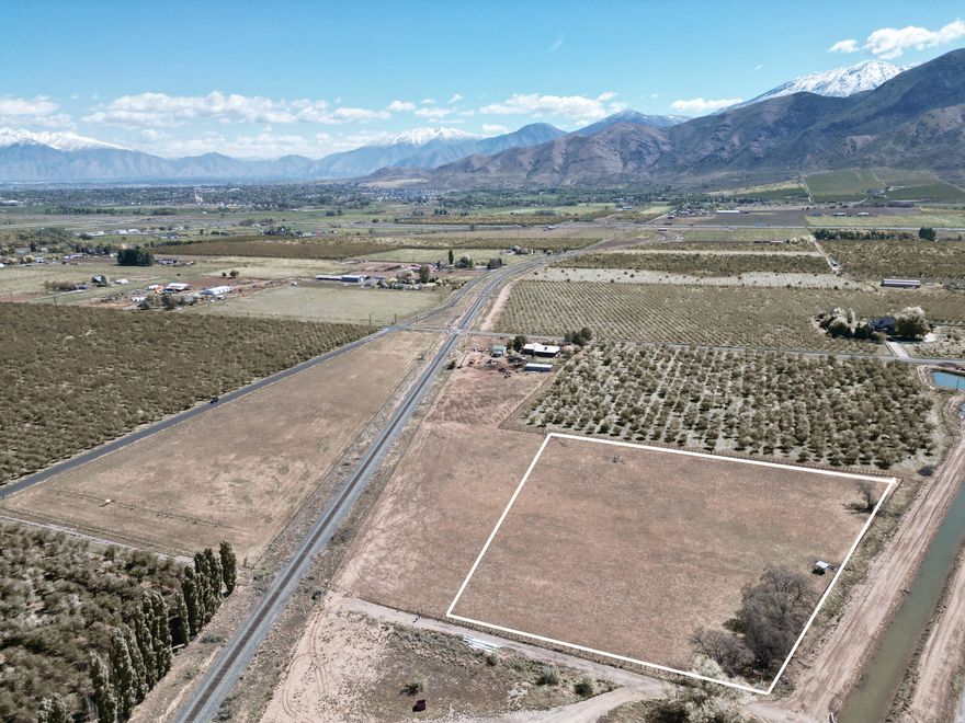 This 3.06-acre residential agricultural parcel offers a great opportunity for those seeking usable land with scenic surroundings. The property includes 6.12 water shares and features pressurized irrigation, making it well-suited for agricultural use or continued livestock grazing. Partially fenced and currently used for cattle, the land is both functional and versatile. Enjoy beautiful mountain and valley views, with the added benefit of being located adjacent to established orchards and a newer development-providing a blend of rural charm and nearby growth.