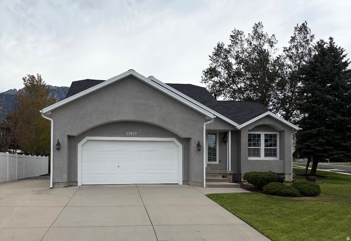 Stucco exterior with a two-car garage, concrete driveway, and front lawn landscaping