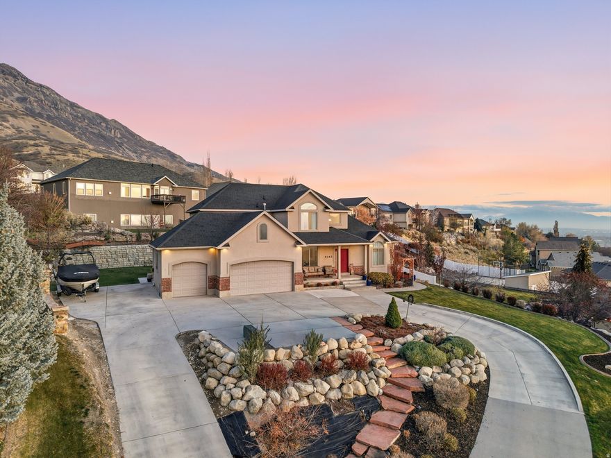 Tucked away in a quiet cul-de-sac on the highly sought-after east bench of Cedar Hills, this stunning home sits on nearly half an acre and captures panoramic valley views framed by a dramatic mountain backdrop. The main floor welcomes you with a warm entryway that opens to a versatile sitting room or office, followed by a bright and spacious family room featuring a fireplace with built-ins on both sides and a wall of windows that fill the space with natural light. The family room flows seamlessly into the dining area and kitchen, which includes a large island, excellent storage, and a layout that works beautifully for everyday living or entertaining. A main-floor primary suite adds comfort, privacy, and convenience. The fully landscaped backyard feels like a retreat, complete with a large pergola, fire pit, mature grapevines, and plenty of room to relax or entertain while enjoying the incredible views. Approved ADU with its own entrance, bedroom, three-quarter bath, laundry, full kitchen, and family room provides exceptional flexibility for multigenerational living, guests, or rental income. Additional features include a heated driveway, RV pad, and close proximity to parks, trails, and Cedar Hills Golf Club, making this a rare east bench opportunity with unbeatable views and versatile living options.