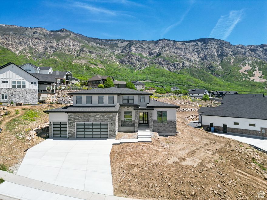 This stunning, custom-built home is a masterpiece of design and functionality. The striking exterior and large double doors makes an elegant first impression, while the versatile floor plan is perfectly suited for both hosting gatherings and enjoying peaceful seclusion. The chef's kitchen is a showstopper with custom cabinets, top of the line appliances and a large butler's pantry that adds both charm and function.  The home offers plenty of natural light with gorgeous mountain views out the back windows. The luxurious primary suite is conveniently located on the main level, and offers breathtaking views of the valley. The spa-inspired primary bath includes double sink, a soaking tub and shower and a large walk-in closet. There's plenty of space upstairs with four large bedrooms, two bathroom and an oversized bonus room. The finished basement provides two additional bedrooms and bathrooms, a second kitchen, additional laundry room, a huge family room and plenty of storage space. Throughout the home, thoughtful design choices shine. This remarkable home blends luxury and comfort into a single package, offering an exceptional lifestyle at the Cove in North Ogden.