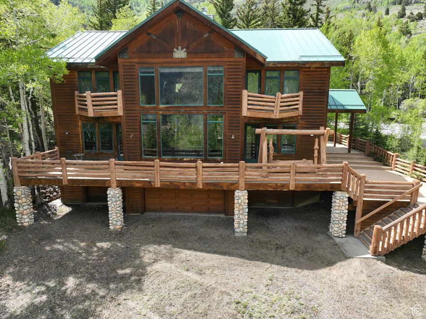 This is your chance to own one of the best cabins in the Fish Lake Basin. At 4,671 square feet, this cabin was built before size restrictions were put in place. It's located on a dead-end road with only 3 other properties, so you'll have minimal traffic. You are well within walking distance to the historic Fish Lake Lodge and Twin Creeks Rec site and boardwalk.  The large East facing windows let you enjoy the rising sun and give you a great view of Fish Lake. You can enjoy the sights and sounds of Twin Creek running right next to your deck that wraps around 3 sides of the cabin. The natural landscaping is low maintenance and invites native animals to use the area. There is power and internet connected and 2 propane tanks to make using this cabin possible to use year-round.   Inside you will immediately notice the beautiful aspen tongue and groove paneling taken from a local ranch commonly known as the Johnson Ranch. The real hard wood floors, limb banisters, live edge pillars, rocked fireplace, and rough-cut beams & trusses give this cabin the rustic aesthetic that is both charming and timeless. The size and scale of the rock floor-to-ceiling fireplace naturally draws attention and becomes a central element of the room. The double-sided aspect of the fireplace on the main level allows the warmth and charm of the fire to be enjoyed from multiple rooms or areas of the cabin, enhancing the sense of openness and flow. 2 Kauba native American statues stand at each side the fireplace. The insert upstairs allows for heat to be distributed throughout the cabin as needed.  The main level has a living room with large East facing windows and 2 outside doors to access the deck. The kitchen has been updated with beautiful countertops, custom cabinets, stainless steel appliances, a large pantry, 2 sinks, and a tall bar. The dining room just off the kitchen has windows on 3 sides to enjoy the views. The master suite offers a large bedroom, walk-in closet with red cedar, a den or office, and a huge bathroom with separate shower and a freestanding tub.  A guest bedroom connects to the hall bath making guests stay more convenient. At the top of the stairs is a large room perfect for entertaining with a custom pool table, gas fireplace insert, and still more of those beautiful views. There are 2 bedrooms, a den/TV room, and 2 bathrooms that offer a lot of flexibility and enhances the cabin's functionality, especially when accommodating more people or wanting separate spaces for different activities. Tuck-under garages make efficient use of limited lot space, which is especially beneficial in areas with strict zoning regulations or uneven terrain. With 5 spaces for vehicles, additional storage, utility room, and laundry room, you will be able to keep things organized and easily available during your stay. There are 3 forced air furnaces and 2 water heaters to help make things more comfortable.  The covered deck on the back of the cabin can be accessed from sliding doors off the den, dining room, and kitchen. It's the perfect spot for outdoor cooking and entertaining. The Twin Creek runs down along both the north and south side of the cabin and is a natural water feature that complements the rustic setting and adds to the overall beauty of the property.