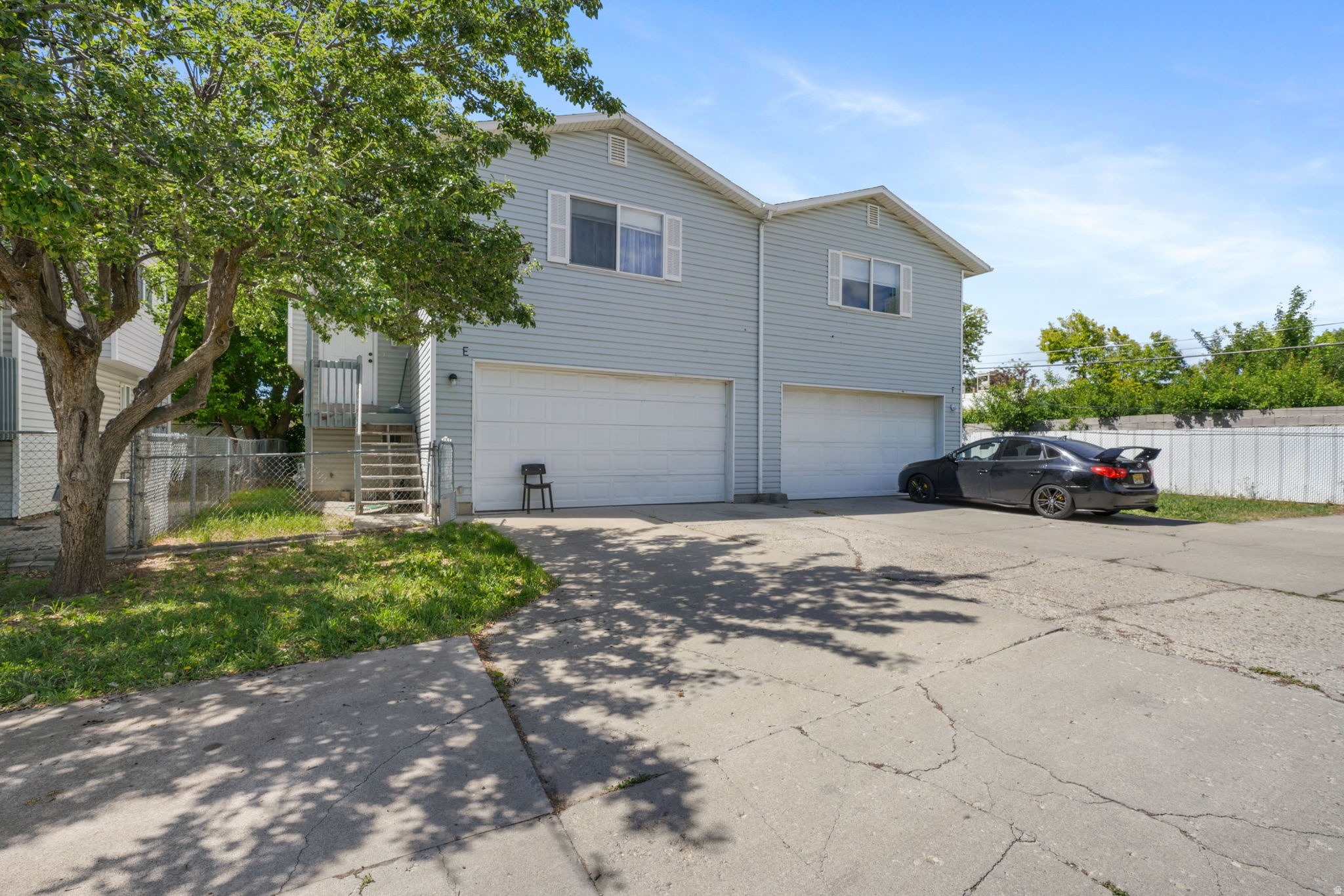 Light blue siding exterior featuring white garage doors and a paved driveway