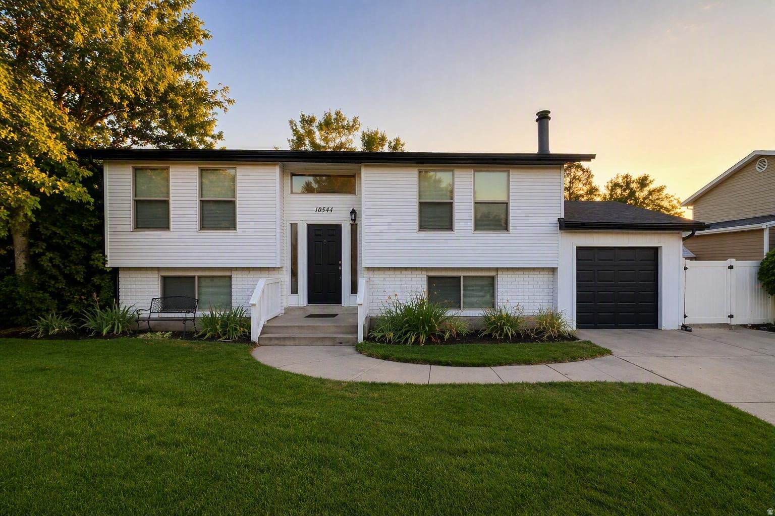 Two-story split-level residence featuring white siding and brick accents