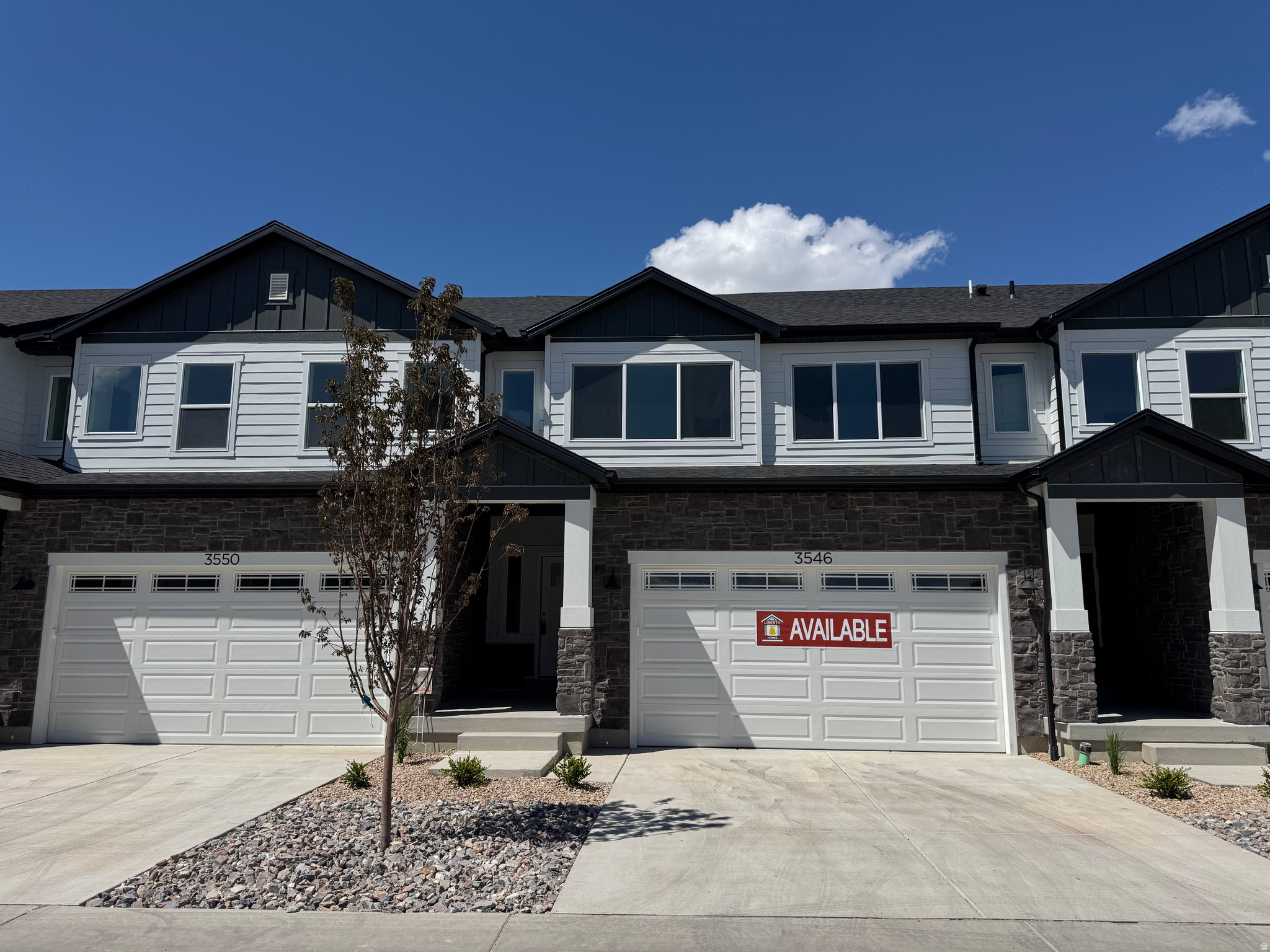 Contemporary townhome facade featuring a stone and siding exterior
