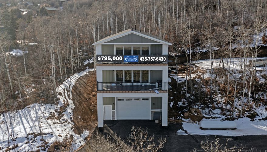 Tucked away in a wooded, private setting, this inviting Bear Lake home offers peaceful surroundings with beautiful lake views enjoyed from two covered balconies. The open kitchen, dining, and living area is designed for gathering, featuring a cozy fireplace and large view windows that frame the natural landscape. A main-level master suite provides comfort and convenience, while the upper level offers three additional bedrooms, a full bathroom, and a second living room with its own fireplace-perfect for relaxing or hosting guests. An extra-long, extra-high garage measuring approximately 30 by 40 feet includes an upper storage room of about 60 square feet, ideal for recreational gear and seasonal storage. The paved driveway and ample parking add ease and accessibility. Outdoor enthusiasts will appreciate the close proximity to The Sinks and Cache National Forest, offering direct access to ATV, UTV, and snowmobile trails, along with opportunities for snowshoeing, mountain biking, and hiking. Beaver Mountain Ski Resort is just 15 minutes away, while Bear Lake State Park Marina and Garden City are only 5 minutes from the property. Two nearby Garden City parks enhance the lifestyle, one featuring a scenic boardwalk to the beach and the other offering a fishing pond and pickleball courts. Please note that short-term rentals are not permitted by the HOA.