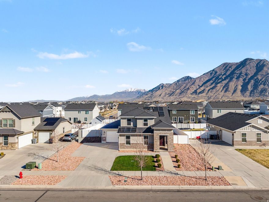 If you've been waiting for a home that actually checks all the boxes, this is it. Nestled in the sought-after Miners Grove community, this two-story charmer delivers the space, style, and lifestyle you've been looking for. The layout is both functional and inviting. The open main living area flows seamlessly from a stylish kitchen featuring granite countertops, rich wood cabinetry, and all appliances included, making it genuinely move-in ready from day one. Upstairs, comfortable bedrooms offer plenty of room to unwind, while the spacious main suite impresses with a walk-in closet and a private en-suite bath. The conveniently located upstairs laundry room comes complete with washer and dryer included.  Step outside to a large, fully fenced yard with a spacious deck, perfect for summer BBQs, evening hangouts, or simply soaking up the mountain views. The roomy three-car garage and ample parking mean there's space for all your vehicles, toys, and guests.  Bonus: solar panels will be paid off at closing, so you start saving on energy cost from the moment you move in. Just minutes from Clyde Recreation Center, parks, schools, shopping, dining, and freeway access, this home makes it easy to enjoy everything Springville has to offer. Use our preferred lender, Travis Lemmon at Creekside Mortgage and get a free appraisal & $1000 closing cost credit.