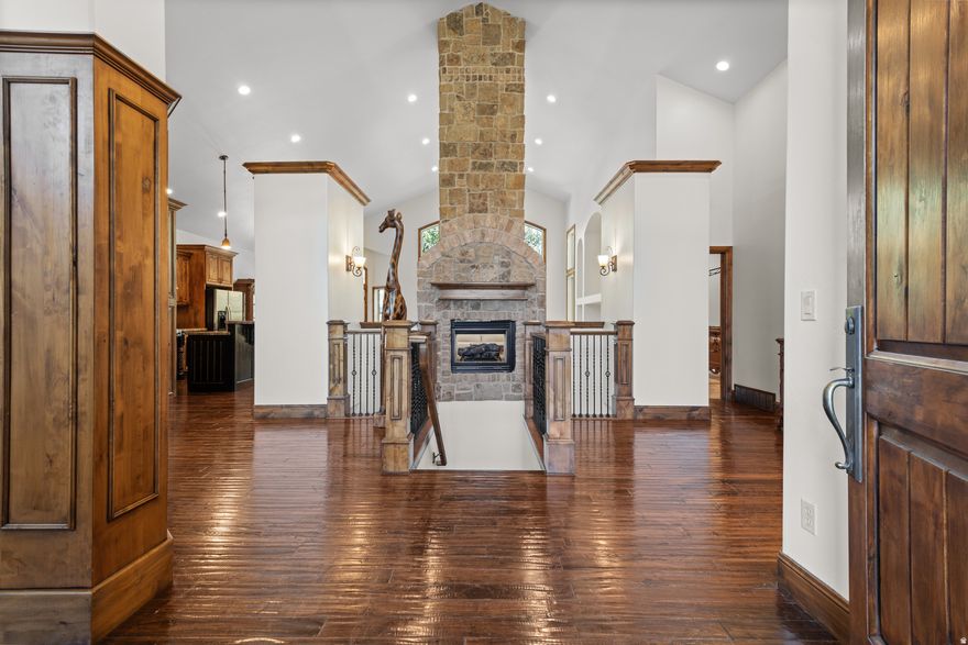 Tucked into a highly desirable Sandy neighborhood and framed by MATURE trees, this home seamlessly blends charm, comfort, and convenience. Just minutes from the Shops at South Town and the new Utah Mammoth facility, you can enjoy dining and shopping nearby while returning to a peaceful, picture-perfect retreat.  Step through a dramatic front entry that evokes the warm, rustic appeal of a SKI LODGE - exposed timber accents and rich finishes set the tone. Inside, a HIGH vaulted ceiling soars above a floor-to-ceiling stone fireplace and hand-scraped hardwood floors throughout. The chef's kitchen features granite counters, stainless appliances, double ovens, and a grand island that opens to sunlit dining and living spaces. Large windows flood the home with natural light and offer serene backyard views (and the occasional family of deer).  The primary suite is a true haven with a luxurious ensuite bath and one of the larger walk-in closets you'll find on the market. Enjoy outdoor living under the pavilion, ideal for relaxing or entertaining beneath the canopy of mature trees. A DEEP two-car garage with the depth to accommodate four cars, plus separate BASEMENT entrance accessible from the garage, complete this unforgettable property.