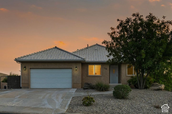 Stucco exterior with a tiled roof, attached garage, and a concrete driveway