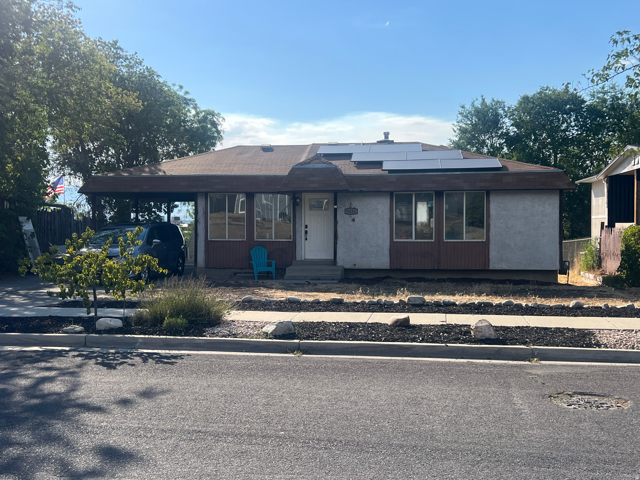 Ranch style home featuring a concrete driveway, carport, solar panels, and peach tree