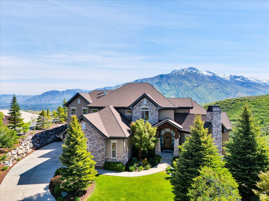 Nestled in the heart of SunCrest, this 5-bedroom, 4-bathroom home stretches across 8,499 square feet of mountain living on a .76-acre lot. You couldn't build this kind of home, on this kind of lot, for this kind of price in today's market. Not even 20 years old, it captures everything SunCrest is known for: fresh air, miles of hiking and biking trails, wide-open space, and views that make you stop mid-sentence. Four decks wrap around the exterior, offering front-row seats Lone Peak, Timpanogos sunrises and twinkling city lights at night. And with a brand-new roof just installed, you get peace of mind to match all that curb appeal. Inside, the main level is all about ease and elegance. It offers true main-floor living with two full bedroom suites. The primary retreat includes a private deck, spa-like ensuite with a walk-in shower, jetted tub, dual vanities, and a roomy walk-in closet. On the opposite side of the main level, a second bedroom also features its own ensuite. Perfect for guests, multigenerational living, or long-stay visitors. The kitchen, dining, and family room flow together seamlessly, making it ideal for both daily life and entertaining. Real hardwood floors, tall ceilings, and windows that frame mountain views add warmth and light throughout. Add in a formal living room, an office with fireplace, and main-floor laundry, and you've got the ideal daily setup. Details like plantation shutters and crown molding add charm and polish throughout. Upstairs, you'll find three additional bedrooms, two bathrooms, a second family room, a game area, and a second laundry room so there's no hauling baskets between floors. The basement is unfinished but well on its way. It features 9- to 11-foot 6-inch ceilings, framing in place, and roughed-in plumbing, and may even qualify as partially finished. The original plans (included) call for 2 full bathrooms, 2 bedrooms, a theater room, laundry, and a wide open family room. Whether you follow the original layout or bring your own vision to life, you'll appreciate the full walkout design and the wraparound deck that steps down to the lower level grassed yard. SunCrest continues to be one of Utah's best-kept secrets, and this home reflects the very best of it. The HOA includes internet, cable, a community clubhouse with a pool and gym, and events that make the neighborhood feel like home. A home this size, on a lot this rare, in a setting this special? That's not just a listing. It's a rare find that actually lives up to the phrase.
