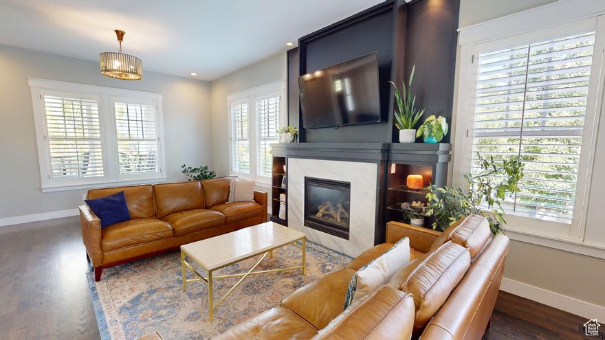 Amid the beautiful homes springing up in Daybreak, this one truly stands out. With its modern craftsman design, this home exudes elegance, blending timeless style with just the right amount of standout features. A spacious front porch, complete with ceiling fans, included porch swing, and inviting sitting areas, makes it the perfect spot to unwind and watch the neighborhood come to life or enjoy views of the mountain and Oquirrh Lake just down the street.  Inside, a formal foyer opens to the dining and living areas, creating a sense of flow and space. The centerpiece of the living room is a stunning marble fireplace with lit shelving, adding both warmth and sophistication. Large windows throughout the home let in an abundance of natural light, highlighting the upgraded lighting, plantation shutters, and rich hardwood floors that tie everything together.  The kitchen is a true showstopper, featuring sleek white shaker cabinets with glass front upper boxes, beautiful granite countertops, and a large island with ample seating. With top-of-the-line Caf smart appliances and glass pendant lighting, it's a space built for both functionality and style. Vaulted 18-foot ceilings open up to the loft, creating an airy, open feel. Spacious walk-in closets complete the bedrooms, and the primary suite is a private oasis with luxurious finishes.  Both the main floor and upper floor feature dedicated laundry rooms, each with included washers and dryers-no more hauling laundry up and down. Recently replaced carpet and a new stair runner add to the home's fresh appeal.  Downstairs, the fully custom finished basement is a highlight. From the executive-style home office, complete with alder cabinetry, wainscoting, wet bar, microwave, and mini-fridge, to the granite fireplace and hickory wood floors, no detail was overlooked. It's a space that must be seen to be fully appreciated. The wet bar adds even more convenience for hosting guests.  Outside, the backyard is a true retreat, featuring a spacious entertainment area with a fire pit sitting area and even an included trampoline-perfect for fun and gatherings. The oversized garage has been thoughtfully finished with mud and paint, offering extra height, included storage, and added length for your convenience.  The home also includes a fully fenced yard, a three-car detached garage, and an extra-long driveway. Across the street, enjoy a park with a walking path that leads to Oquirrh Lake, as well as nearby amenities like a playground, pool, and playing field.  This home offers an exceptional blend of style, function, and comfort both inside and out.  Square footage figures are provided as a courtesy estimate only and were obtained from County Records.  Buyer is advised to obtain an independent measurement.