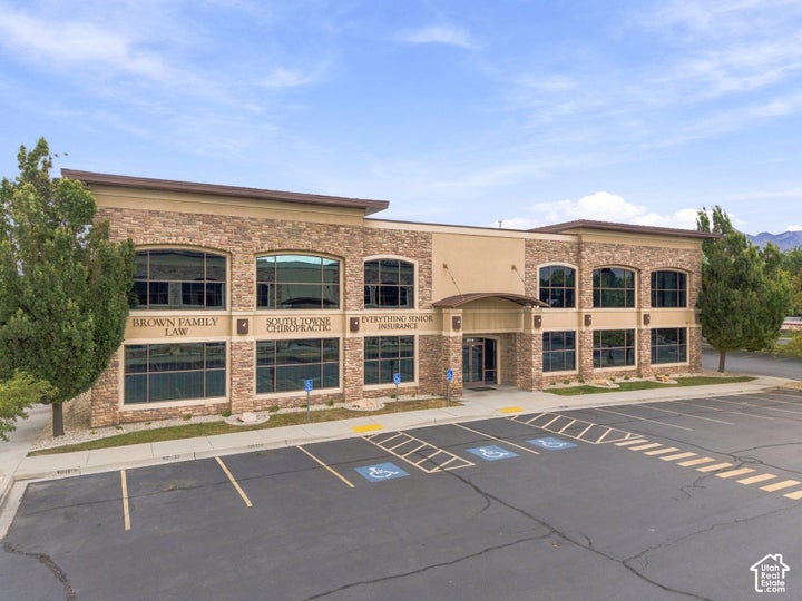 Two-story commercial building featuring a stone veneer exterior, expansive glass window panels, a covered entry, and…