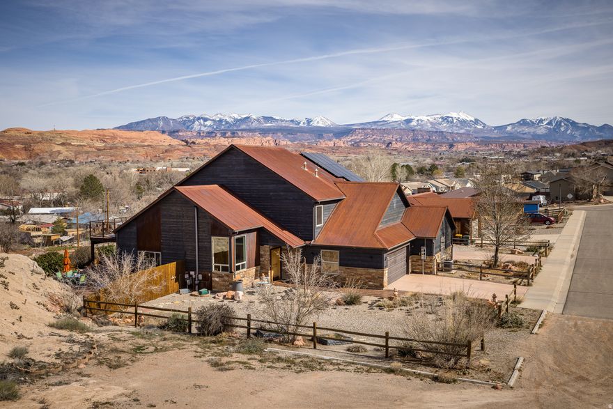 Exceptional views! Twin home with sweeping vistas of the La Sal Mountains and surrounding red rock, offering end of the road privacy. This uniquely designed two story home sits on .15 acres and features a two car garage along with warm, inviting finishes throughout.  The main level offers two bedrooms and two full baths, while the upper level includes an additional bedroom and full bath, ideal for guests or added separation of space. The living room is anchored by a floor to ceiling stone fireplace, creating a striking focal point and cozy gathering space, with direct access to the patio that extends the living space outdoors. Architectural angles throughout add visual interest and give the home a distinctive character.  The kitchen features large, expansive windows, stainless steel appliances, and modern pendant lighting, with a separate dining area and breakfast bar offering both function and flexibility.  Outdoor living is a standout feature, with a gorgeous stone patio on the lower level and a spacious upper deck that spans the length of the home, perfect for taking in the surrounding scenery.  The property is framed by simple native landscaping for low maintenance living and a natural desert feel.