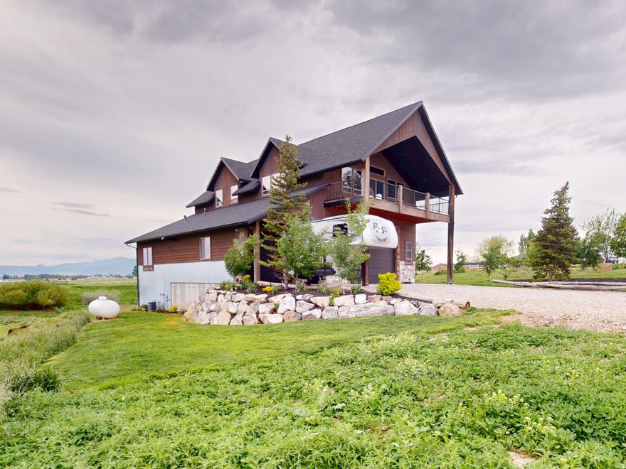 Perched atop a gently rolling hill and surrounded by sweeping mountain views in every direction, this custom-built home is a rare find. Nearly every window frames a postcard-worthy vista, while the 5.5-acre property offers serenity, space, and sustainability. A year-round stream flows peacefully alongside a scenic pond-perfect for enjoying quiet evenings and watching sunsets over the western range. Water rights for irrigation and a natural spring provide a sustainable, culinary-grade freshwater supply. Designed with both comfort and utility in mind, the lower level features an oversized 5-car garage-ideal for RVs, recreational toys, and workshop space. It's equipped with wiring for a mechanical lift and a 12+ foot high door for your largest vehicles. Upstairs, an expansive covered balcony invites you to start your mornings with sunrise coffee or unwind with evening grilling. Inside, rustic charm meets thoughtful design, with vaulted ceilings, a stunning stone fireplace, and walls clad in locally sourced, reclaimed barn wood. The spacious primary suite includes dual vanities, a walk-in shower, and a generous walk-in closet. The lower level also offers a full bath and a flexible office space-ideal for a guest suite, gym, hobby room, or lounge. A separate storage room with built-in shelving and a roll-up door provides ample space for outdoor gear and lawn equipment. Just 3 miles from the heart of picturesque Preston, Idaho and 23 miles to Logan, Utah, you'll enjoy the peace of country living with the convenience of nearby amenities. Several furnishings and key features convey, including a propane tank, water softener, sofa, kitchen table and chairs, barstools, and washer/dryer-making this move-in ready. This is more than a home-it's a lifestyle. Call the listing agent today to schedule your private tour of this one-of-a-kind sanctuary.