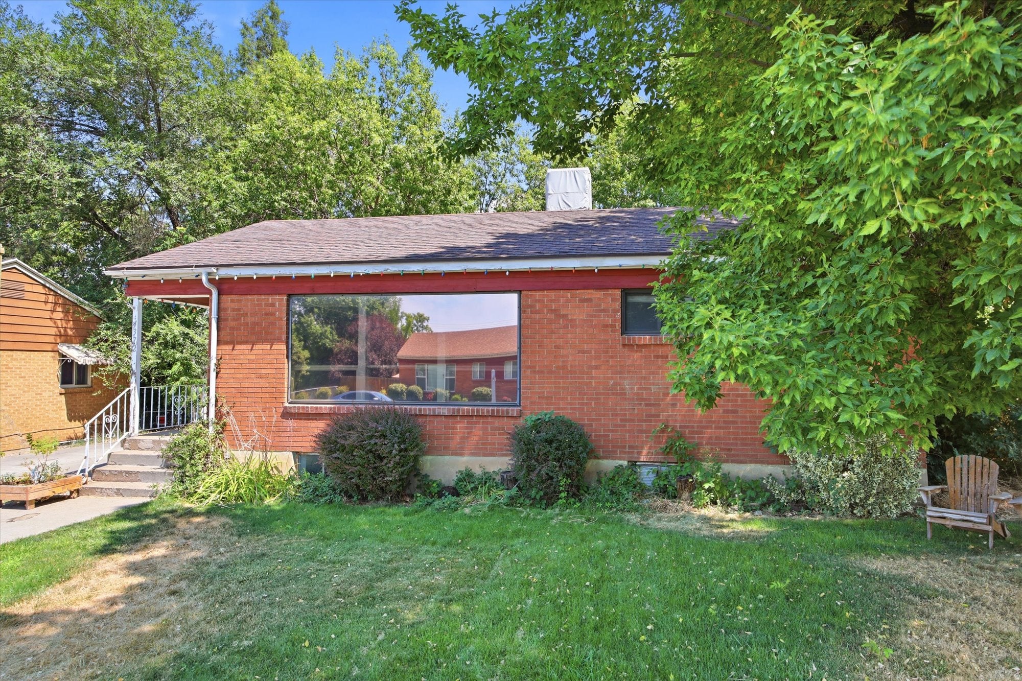 Brick exterior with a large picture window, covered entry, and established landscaping