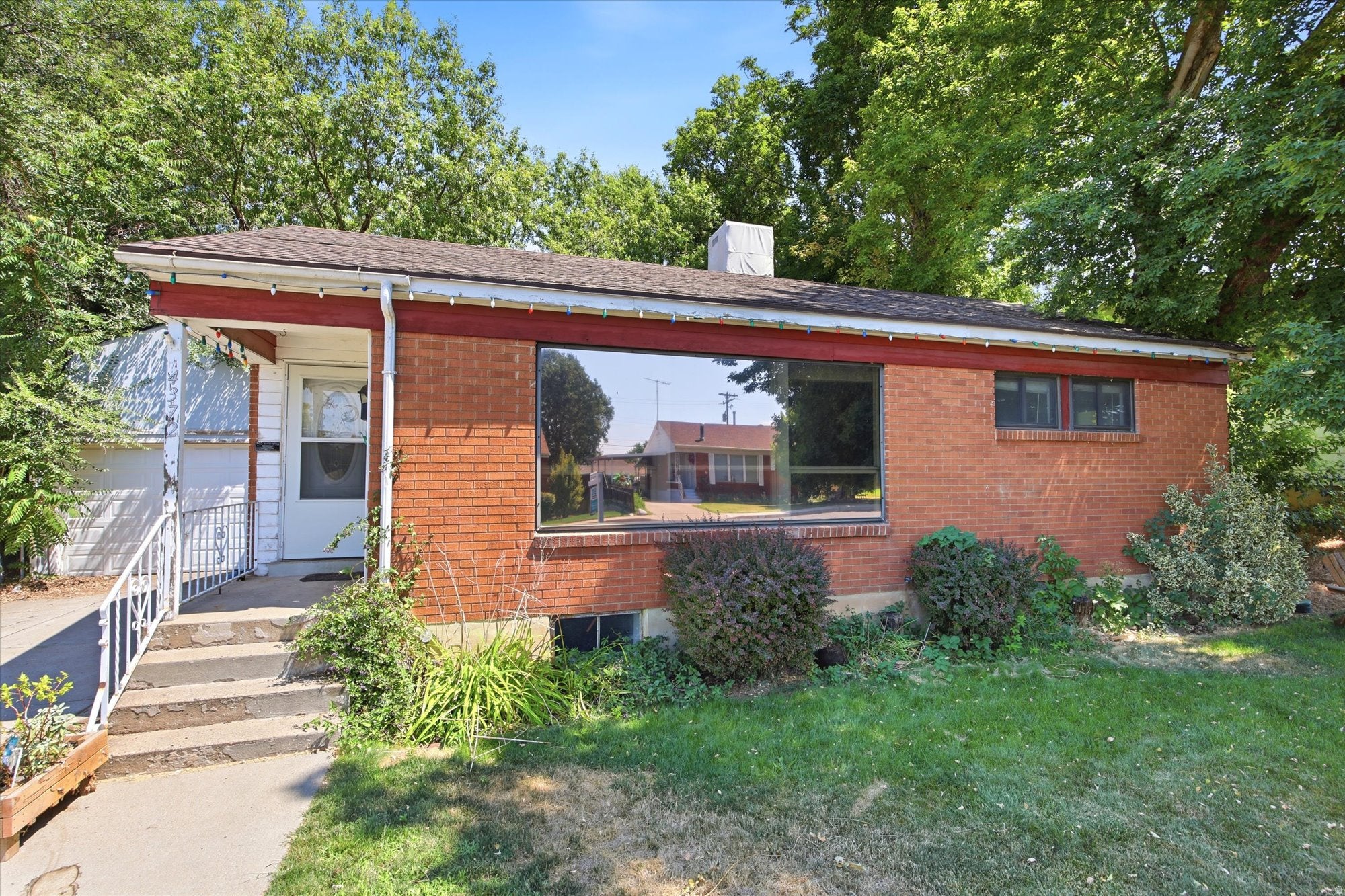 Brick exterior with a large picture window, covered entry, and established landscaping