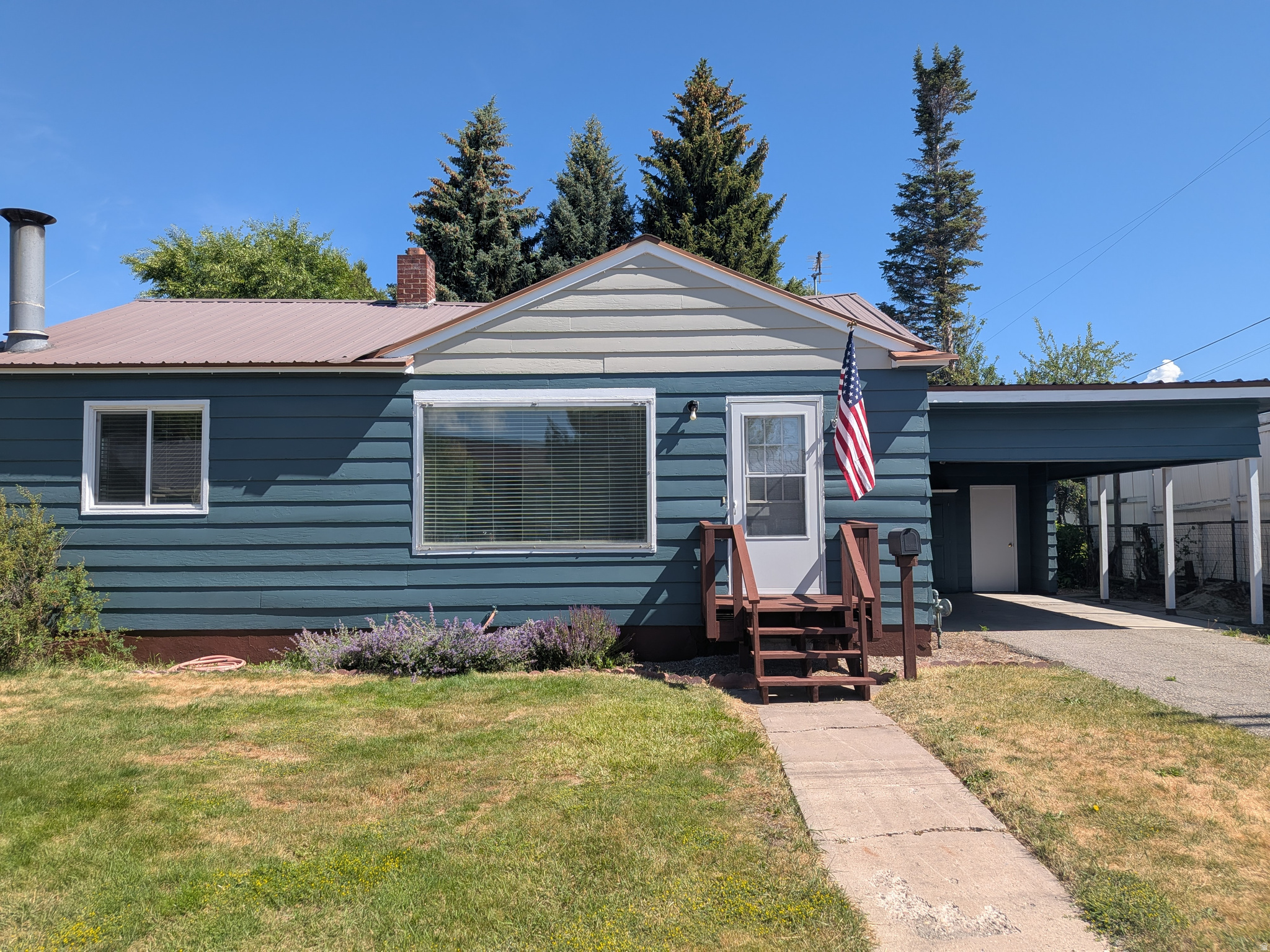Blue horizontal siding exterior with a metal roof and a covered carport