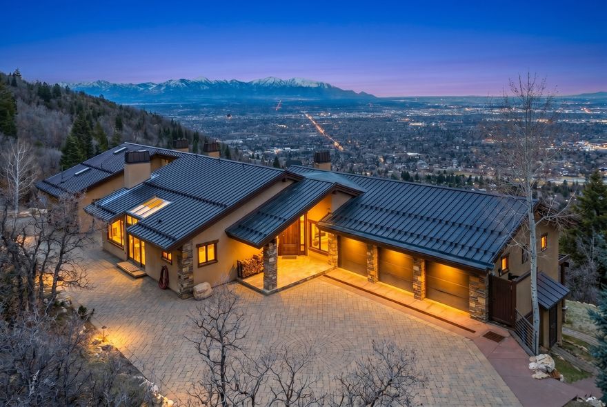Nestled on a secluded 1.42 acre lot, this gated mountain retreat on Zarahemla Drive is a one of a kind property that you won't want to miss. The soaring windows offer breathtaking views and an abundance of natural light, making this residence a true sanctuary. Step inside and be immediately captivated by the rich, handcrafted woodwork that adorns every corner, from the wood beams in the vaulted ceilings to the custom cabinetry in the entertainers kitchen. Every sunset in this home makes you feel like you're on vacation. Through the sliding glass doors you will find your private deck, where nature and luxury living meet. Unwind in the stunning infinity hot tub, perfectly positioned to offer uninterrupted, panoramic views of the surrounding mountains and city skyline - where the sunsets are unmatched anywhere in Olympus Cove. Each evening the sky transforms into an unforgettable panoramic display, painting the sky in changing hues that must be seen to be believed. The primary suite features its own fireplace and en-suite bathroom with a deep walk in closet. The open-concept floor plan is designed for both entertaining and relaxed living. The large stone fireplace in the great room sets the tone for winter nights, while the wall of windows brings the beauty of the mountains indoors. On the lower level, an indoor 32 ft. heated pool and spa allowing year-round enjoyment and sweeping views of the entire valley, complemented by a fully equipped wet bar, a ping pong table, pool table room and a fireplace. Three additional bedrooms and bathrooms on this level will accommodate your needs. The private lane with a heated driveway and three-plus car garage is perfect for storing your cars and bikes. The maintenance free copper roof and chimneys add lasting durability to this exceptional home. With breathtaking views, exceptional craftsmanship, and sophisticated design, this home defines mountain living at its finest.