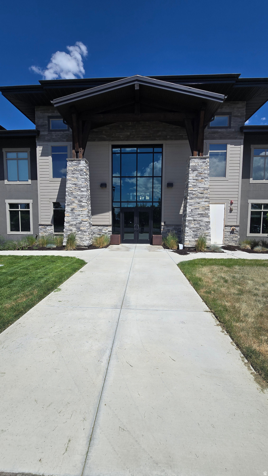 Modern exterior featuring a prominent covered entry with stone columns and wood beam accents