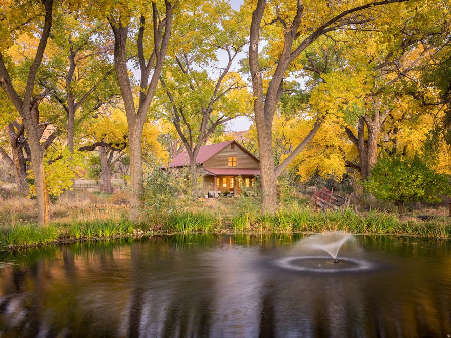 Oasis Under the Cottonwoods!  This private and secluded ranchette, rich with canopies of seasonal colors and shade, sits within a protected wildlife conservation corridor connecting Pack Creek to Mill Creek, offering a rare blend of tranquility and accessibility. Lush and green amidst the high desert's deep red earth, it's a peaceful retreat just minutes from the heart of Moab's adventure, recreation, and services. Enjoy direct access to hiking, biking, horseback riding, and golf, all from your doorstep. The property includes an abundance of water with a well with deeded water rights, additional surface irrigation shares, fed into an upgraded irrigation system featuring wheel lines, hand lines, underground lines, and stunning irrigation pond. The large hay field yields up to four cuttings per year, with two additional smaller pastures ideal for rotational horse grazing. The conservation easement protects the land's natural beauty for generations while allowing for a corral, barn, caretaker's home, guest house, or educational center, as well as a garage, shop, or home expansion. An attractive three-bedroom home is move-in ready and features refinished hardwood floors, vaulted tongue and groove ceilings, a new energy-efficient mini-split climate control, hot water radiant heat,  modern appliances, as well as all furnishings. This expansive homestead your soul has been seeking is ready for your connection and immediate enjoyment.  Square footage figures are provided as a courtesy estimate only and were obtained from images.  Buyer is advised to obtain an independent measurement.