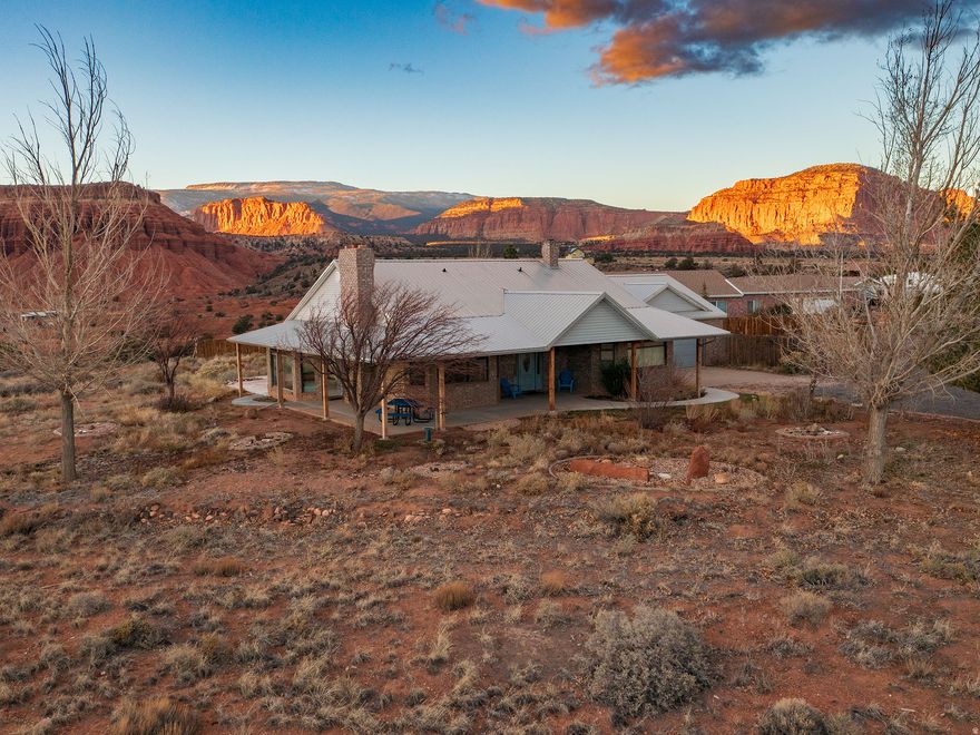 Experience unobstructed red cliff vistas and timeless desert serenity at 397 N Wendy Drive in Torrey, Utah. Built in 1993 and lovingly updated by the former Superintendent of Capitol Reef National Park, this home was intentionally designed to frame the region's most iconic scenery. Perfectly placed windows capture dramatic red rock cliffs, endless night skies, and the peaceful rhythms of Wayne County living. Step inside to an inviting open-concept main floor featuring a spacious entryway, living and dining areas, and an adjoining kitchen ideal for gathering. The updated kitchen offers abundant cabinetry, granite countertops, a peninsula plus large island, gas and electric cooktops, double oven, and a generous pantry, perfect for everyday living and entertaining. The sunroom on the northwest side of the home is a highlight, offering panoramic views of the cliffs and star-filled skies. The main-level primary bedroom includes a large ensuite bathroom with a walk-in shower and a luxurious jetted tub. A convenient laundry room connects directly to the oversized 2+ car garage, complete with a built-in workbench and mud-free entry. The lower level features easy-care insulated luxury vinyl flooring throughout, four versatile bedrooms (ideal as guest rooms, offices, or creative spaces), a full bathroom, and a comfortable family room. Recent upgrades include central air and a heat pump to enhance year-round comfort. Enjoy outdoor living on the wide covered porch that wraps two sides of the home, offering sweeping views of the red rock cliffs, Boulder Mountain, and the Henry Mountains. The yard is designed for low maintenance with minimal landscaping and shade trees for comfort and simplicity. This property includes Torrey Town water, and access roads are maintained by Torrey Town. All appliances are included. Just minutes from Capitol Reef National Park and surrounded by world-class public lands, this home is the perfect basecamp for adventure, tranquility, and breathtaking beauty.  Square footage figures are provided as a courtesy estimate only and were obtained from the county.  Buyer is advised to obtain an independent measurement.
