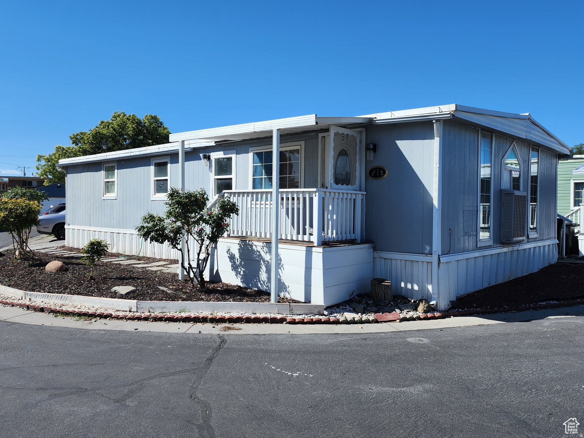Light blue exterior with white trim and a covered front porch featuring white railings