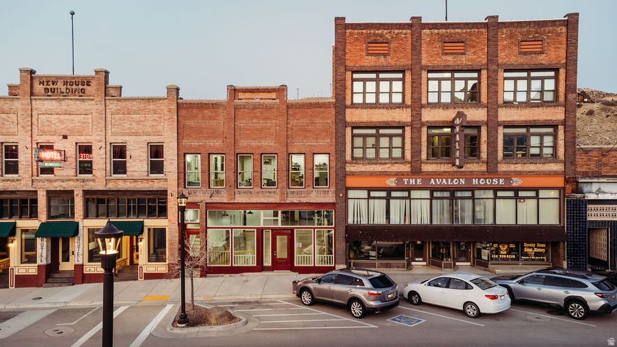 Discover this beautifully restored tri-level building on historic Helper Main Street, where thoughtful artistry meets modern functionality. This fully renovated space preserves its rich history, ensuring each detail reflects both sophistication and intention.  The main level offers over 3,000 square feet of open space, showcasing original red douglas fir flooring, 20-foot ceilings, a private bathroom, and front and back entrances, making it ideal for a gallery or retail space.  Above, the living quarters feature a private entrance, a loft-style living area and stunning views. This level includes five skylights, three bathrooms, four bedrooms-two of which are en suites. Enjoy the balcony off the primary bedroom and private entrance facing the Price River and views of balance rock. All countertops throughout are hand crafted from the building's reclaimed materials. You'll also find ample gallery walls perfect for displaying art. Additionally, there is the convenience of a laundry room.  The lower level, with its own entrance, includes a kitchen, laundry, 3/4 bath, and plenty of open space inviting your creativity.  This historic building has all-new electrical and plumbing systems, along with modern windows, lighting, and new roof. Each floor is thoughtfully zoned with its own air conditioning and heating units, ensuring both comfort and efficiency throughout the property.  Enjoy sweeping views of the Book Cliffs and the nearby river.. This versatile space serves as an inspired studio, gallery, and  unique living area, where every corner tells a story.   Square footage figures are provided as a courtesy estimate only and were obtained from County Records. Buyer is advised to obtain an independent measurement.