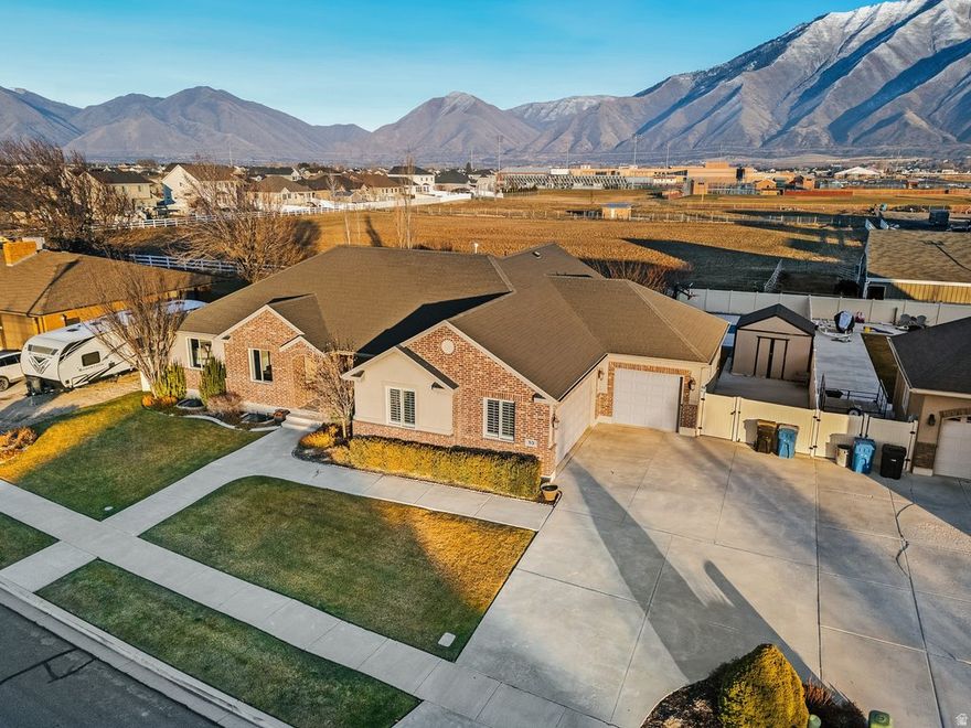 This stunning custom-built home is located in a highly desirable neighborhood near the new Spanish Fork LDS Temple and Harmons (both coming soon), with close proximity to Maple Mountain High School and Sierra Bonita Elementary, offering an exceptional blend of luxury, space, and convenience. Designed for both entertaining and everyday living, the fully landscaped, oversized yard is a true showstopper. Enjoy a sports court perfect for basketball or pickleball, a hot tub, gazebo, and a large open yard ideal for gatherings and play. The property also includes a 14x34 RV pad, a 12x12 shed, and ample parking and storage options. Inside, the home showcases thoughtful craftsmanship and high-end finishes throughout. Features include bamboo wood flooring, granite countertops, knotty alder cabinetry, and plantation shutters. An oversized dining area flows seamlessly into the main living area with a vaulted ceiling showcasing a beautiful wood beam, creating the perfect space for large gatherings, holidays, and entertaining. The layout offers both functionality and flexibility with a dedicated office and piano room, glass French doors leading to the office space. The living spaces feel open, warm, and intentionally designed. The media room is a standout feature, complete with custom-built media cabinetry, a mini fridge and microwave, and a custom sectional designed specifically for the space, included in the sale. This room is ideal for movie nights, game days, and entertaining guests. The primary suite offers a spa-like retreat featuring a walk-in shower, jetted tub, and walk-in closet. Throughout the home, bedrooms are generously sized with walk-in closets and built-in shelving. The home includes 3 bedrooms and 2.5 bathrooms upstairs, along with 4 bedrooms and 1.75 bathrooms downstairs. The Jack-and-Jill bathroom is exceptionally well designed, offering separate closets and separate vanities for each bedroom, while sharing the tub and toilet, providing both privacy and convenience. Downstairs laundry hookups add additional flexibility and functionality. Storage and utility were thoughtfully planned with a large cold storage room, spacious HVAC/storage room with epoxy flooring, extra storage throughout, a water softener, and two water heaters. The 3-car garage is fully finished with epoxy flooring, custom cubbies and lockers, and abundant space for organization and hobbies. This is a rare opportunity to own a truly custom home that delivers on location, lifestyle, storage, and design, perfect for entertaining, everyday living, and everything in between.