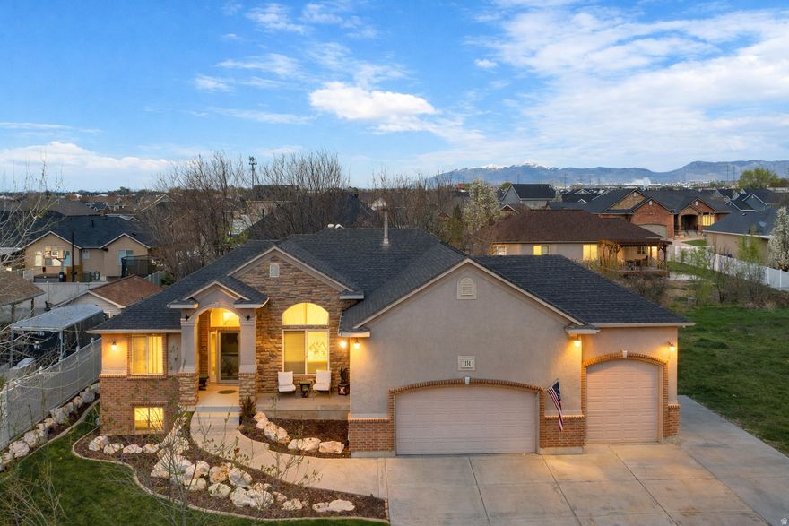 Custom-built rambler in the highly sought-after Hawthorne community in Syracuse UT, offering over 3,600 sq ft of elevated living on a spacious .30-acre lot.  The main level showcases a bright, open layout with refined finishes throughout, including a designer kitchen with two-tone cabinetry, granite countertops, and a seamless flow into the great room-perfect for both everyday living and entertaining. The expansive primary suite is designed as a true private retreat, complemented by a spa-inspired bath featuring a soaking tub and separate shower.  The fully finished walkout basement features 9-foot ceilings, a spacious family room with direct outdoor access, and a custom built-in bar with excellent potential to convert into a full secondary kitchen-ideal for entertaining or multi-generational living.  Step outside to a beautifully landscaped backyard retreat complete with a firepit, creating the perfect setting for relaxing evenings or hosting guests.