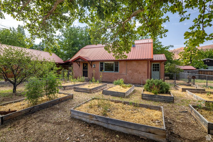 CLASSIC FARMHOUSE CHARM Every corner of this home radiates charm, with unique details that celebrate local artistic flair and quality artisan craftmanship with La Sal milled pine wood features throughout. Whether you're basking in the enchanting morning light next to the warm gas stove, or enjoying the luxury of the private backyard space, this home is sure to be a place of comfort and incredible convenience for years to come. The open kitchen features gorgeous butcher block wood counters, stunning glass cabinets, a five-burner stainless steel stove, four-door refrigerator, a formal dining area, and a cozy bistro nook overlooking the quintessential Americana ball fields that hosts games and festivals of multiple cultures.  With plaster walls and refurbished oak flooring throughout, the main level of the home also includes the primary bedroom which offers patio access to one of two patios, and the shared spacious bathroom with soaking tub. Up the stairs, you will find additional living space, or a secluded secondary bedroom, with vaulted ceilings and offering abundant closet spaces. Step outside to the enclosed yard space where a small orchard thrives with cherry, apple, pear and peach trees, and several built raised beds promise seasons of fresh, homegrown produce. Got gear? The 350 square foot basement offers spacious secured on-site storage.  Located in the heart of Moab, this property combines creative living with urban access to the Mill Creek Parkway, local parks, grocery stores, restaurants and all other attractions that make 'Old Town' downtown living a dream.  Square footage figures are provided as a courtesy estimate only and were obtained from images.  Buyer is advised to obtain an independent measurement.