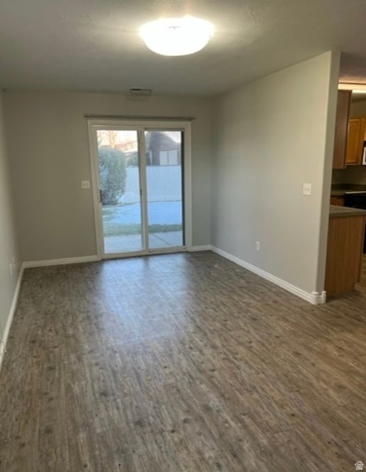 Spacious room featuring wood-finish flooring, light grey walls, and white baseboards