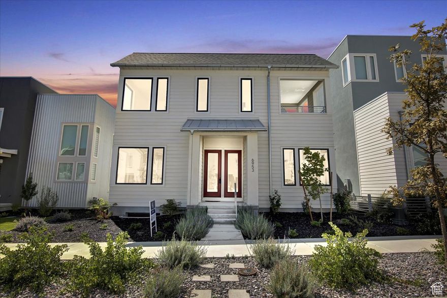 This award-winning home combines modern luxury with thoughtful design, just moments from Daybreak's highly anticipated Watercourse. Bright and open, the main living area is filled with natural light and features expansive sliding glass doors that extend your living space onto a spacious patio-perfect for everything from quiet mornings to lively gatherings. The chef's kitchen flows seamlessly into the living room, creating a warm and inviting atmosphere for entertaining or everyday living. Highlights include a butler's pantry, top-of-the-line appliances, and built-in bookshelves that add both style and function. Retreat to the serene primary suite, complete with large windows, a walk-in closet, and a spa-inspired ensuite bathroom featuring a stunning tile shower and a freestanding soaking tub. Step outside to your oasis, where there is a covered patio to create the perfect setting for memorable evenings under the stars. A brand-new hot tub is included (not yet hooked up), is on the upstairs deck offering even more opportunity for relaxation. The finished basement adds extra versatility with a rough-in for a wet bar-ideal for game nights or casual entertaining. Premium upgrades include oversized interior doors, enhanced window packages, and two covered patios to enjoy the outdoors in any weather. Located within walking distance of outdoor recreation, including paddleboarding at the Watercourse, Lookout Park, and local favorites like Swig, this home delivers the lifestyle you've been dreaming of.