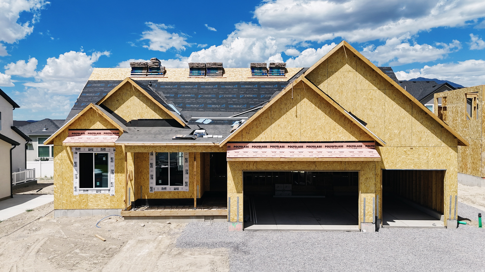 New construction property featuring a three-car garage, multiple gables, and a partial roof installation