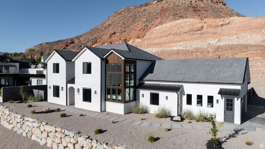 Welcome to this beautifully designed custom home, where modern elegance meets timeless design. Situated in the new neighborhood in Washington, Utah. This two-story masterpiece features clean lines and a striking window tower that floods the home with natural light and showcases the surrounding red rock landscape. Step inside to discover soaring ceilings, expansive windows, and an open-concept layout designed for both luxury and comfort. The spacious living areas are perfect for entertaining, while the chef's kitchen boasts premium finishes, custom cabinetry, and high-end appliances and hidden pantry with plenty of storage! DownStairs, The primary suite complete with spa-like ensuite bathroom is located downstairs. As well is a seperate in home office or 5th bedroom. With built in Desk and closet. Upstairs, you'll find well-appointed bedrooms with plenty of natural light and views. A large living room as well as a bonus room above the garage with access to a bonus storage room. Outside, enjoy desert landscaping and a peaceful setting that blends seamlessly with the Southern Utah terrain. The lot offers privacy, ( huge rock wall that pictures don't do justice) clean desert views, and is just minutes from hiking trails, golf courses, and downtown conveniences. Whether you're watching the sun dip behind the red cliffs or relaxing in the abundant natural light that fills every room, this home delivers the ultimate in modern desert living. Recently appraised on May 30th 2025. 4132 SQFT .5 Acre Lot 2x6 construction Upgraded Insulation as well as many other upgrades.