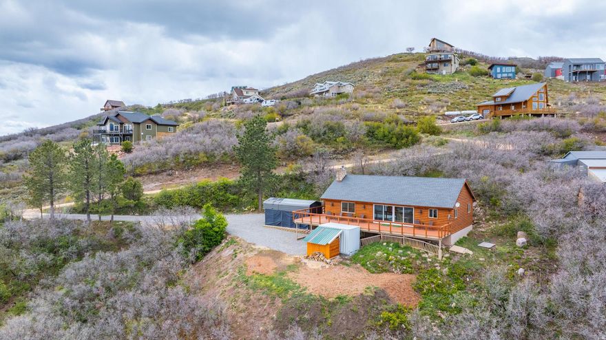 Beautifully remodeled mountain retreat surrounded by nature with spectacular views of Rockport Reservoir and the Uinta Mountains! This charming cabin features soaring vaulted ceilings, expansive windows, and an incredible enclosed sunroom designed to capture the breathtaking scenery year-round-perfect for relaxing, entertaining, or simply soaking in the peaceful mountain setting. The spacious feel continues outdoors with a massive 694 sq. ft. wrap-around deck offering even more room to enjoy the stunning views, plus an additional 126 sq. ft. loft space. With approximately 9,300 gallons of total water storage capacity-more than enough for the winter months-this home is as practical as it is beautiful. Enjoy efficient heating with a gas furnace and fireplace/stove insert, while taking advantage of nearby boating, fishing, biking, skiing, hiking, and everything the Wasatch Back has to offer, including the dining and nightlife of Park City. The property has seen extensive upgrades since 2023. Major improvements include a new heater with an ultraviolet air filter, Nest thermostat installation, a full roof replacement with new sheathing and shingles, upgraded attic and sunroom insulation increased to approximately R49, and a new refrigerator. Additional exterior enhancements include oak brush removal near the deck, a tiered parking system with a 24x10 RV cover, and expansion of the northeast side of the property by about 1,000 square feet with added dirt and leveling. In 2024, a stone wall widened the driveway, gravel was added throughout, new front and downstairs doors with improved R-value were installed along with new storm doors, the septic system was cleaned, and a woodshed with capacity for about two cords of wood was built. In 2025, a 10x18 one-car covered carport was added, water tanks were relocated and protected with sturdy watershed structures, and electrical wiring with heat tape was installed to help prevent freezing. In 2026, the gravel driveway work was completed and new carpet was installed in the living room. Whether you're looking for a full-time residence or the perfect mountain getaway, this one is not to be missed!