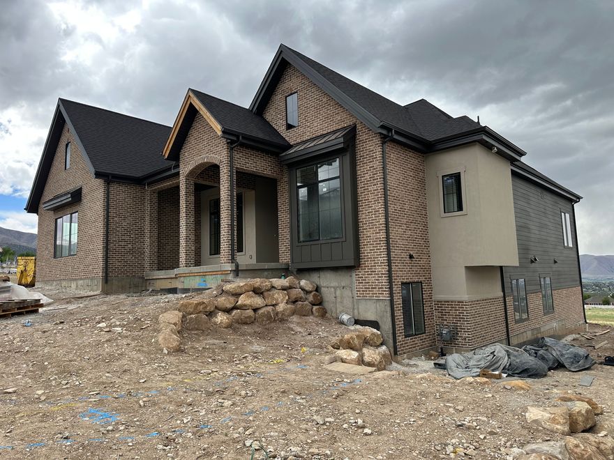 Welcome to Cougar House 14, a fully custom home in the highly sought-after Highlands at Elk Ridge subdivision-where luxury design meets purpose. With stunning views from nearly every window, this home was thoughtfully crafted to deliver elevated living, exceptional comfort, and lasting quality. The main level features soaring ceilings up to 13 feet, expansive high-efficiency windows, and designer finishes throughout. The open layout flows effortlessly to a massive 523 sq ft deck, with a matching covered patio below-creating incredible outdoor living space without the added square footage cost. The walkout basement is equally impressive, featuring a dedicated theater room designed for next-level acoustics (tucked beneath the third-car garage), plus a full-size kitchenette with sink conveniently located nearby-perfect for entertaining. A premium sound attenuation system was also added between living areas and the ADU to reduce both airborne and impact noise, providing excellent privacy and comfort. The basement also includes a private-entry 2-bedroom, 1-bath ADU with its own spacious kitchen, dining and family room, and private laundry-ideal for multigenerational living, guests, or rental income. This home was built with true high-performance construction in mind: ZIPS exterior sheathing, Advantech subflooring, and patented BIBS insulation (R24 walls and R50 attic), all Energy Rated Homes of Utah certified with a targeted HERS score of .65 or better for a 5-star+ rating. The HVAC system is 96% efficient, two-stage, zoned, and designed for multiple thermostats-delivering comfort and efficiency year-round. Additional highlights include upgraded plumbing fixtures, a stunning 60" Montigo Del Ray linear fireplace with Venetian plaster surround, custom fabricated railings, epoxy garage floors with tile stamp finish, custom tile backsplashes, 3-tone paint, custom closet organizers with dresser island, and a premium LG appliance package. Even more meaningful-proceeds from this home will go toward scholarships for BYU students, making this not only a remarkable home, but a chance to invest in future leaders.  Square footage figures are provided as a courtesy estimate only and were obtained from building plans.  Buyer is advised to obtain an independent measurement. Buyer is responsible to verify all information.