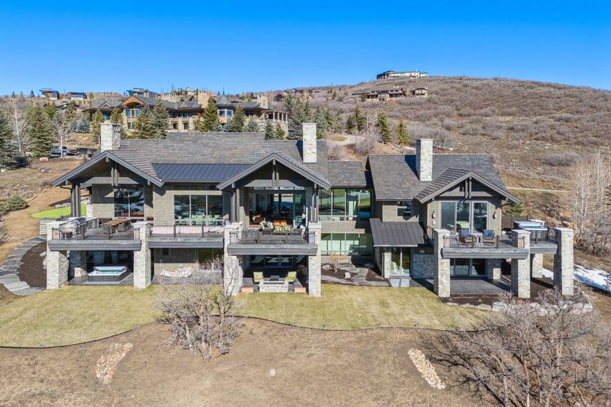 This estate, completed in December 2024, was built by Dowie/Wing Construction with Jonathan DeGray as the architect. Thoughtfully designed with floor-to-ceiling windows and doors, the home seamlessly brings the surrounding mountain landscape indoors. The floorplan offers true main-level living.  The primary suite is a private retreat featuring dual walk-in closets, a spacious private deck with hot tub, fireplace, and a generously appointed primary bath. Even the dramatic glass front door frames mountain views upon arrival.  The Great Room encompasses the kitchen, hidden pantry, two fireplaces, a secondary TV lounge, and a fully enclosed glass wine wall. The kitchen showcases one of the longest breakfast bars available, enhancing both elegance and functionality. Appliances are top-tier, including Sub-Zero, Miele, and an ILVE Majestic Italian 7+ burner range.  The heated three-car garage is fully equipped with water, drains, and a dog wash station.  The lower level offers a second family room, exercise room, three additional en-suite bedrooms (including a bunk room), office, laundry, wet bar-and as a unique bonus, two secret rooms.  Glenwild new construction home with ski and Uinta Mountain views.