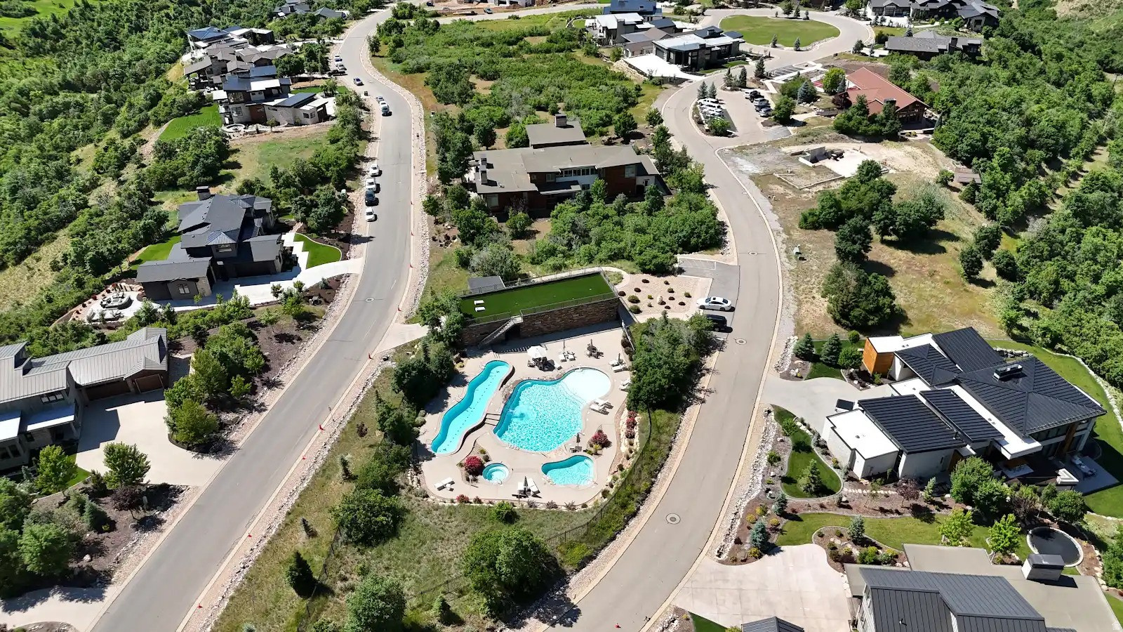 Community amenities featuring a multi-pool aquatic area with a water slide, integrated hot tub, and surrounding lounge space