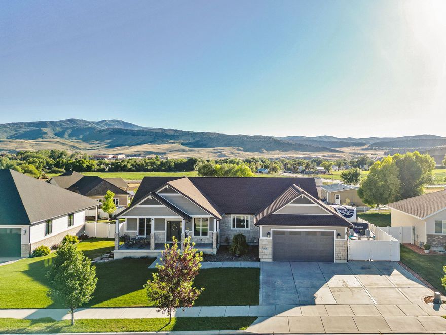 Enjoy the ease of small-town living with peaceful mountain surroundings in this beautifully designed home, offering comfort, quality, and style throughout. Inside, an open-concept layout with soaring 11' ceilings creates a bright, spacious feel, complemented by high-end craftsmanship.  The backyard is a true retreat-relax under the custom pergola or unwind in the covered hot tub while taking in stunning mountain views. The large lot also features covered front and back patios, perfect for morning coffee or evening entertaining.  A full daylight walkout basement adds flexibility with two huge storage rooms, a secondary family/theater room with surround sound, a home gym, and abundant natural light-ideal for a future mother-in-law suite or long-term rental potential.  An oversized garage offers ample parking and storage, plus dedicated RV and boat parking along the side. Whether you're seeking quiet living or a home built for entertaining, this property checks all the boxes.