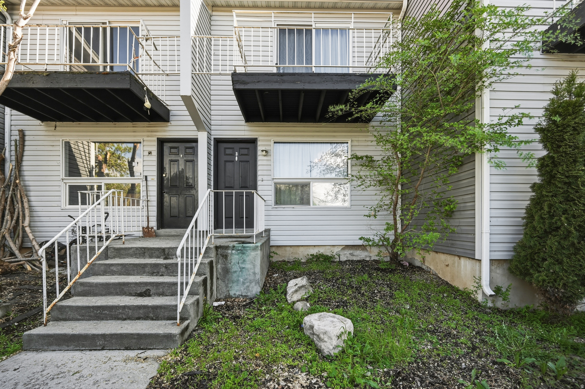 Multi-level townhouse exterior featuring light-colored siding and two distinct entryways