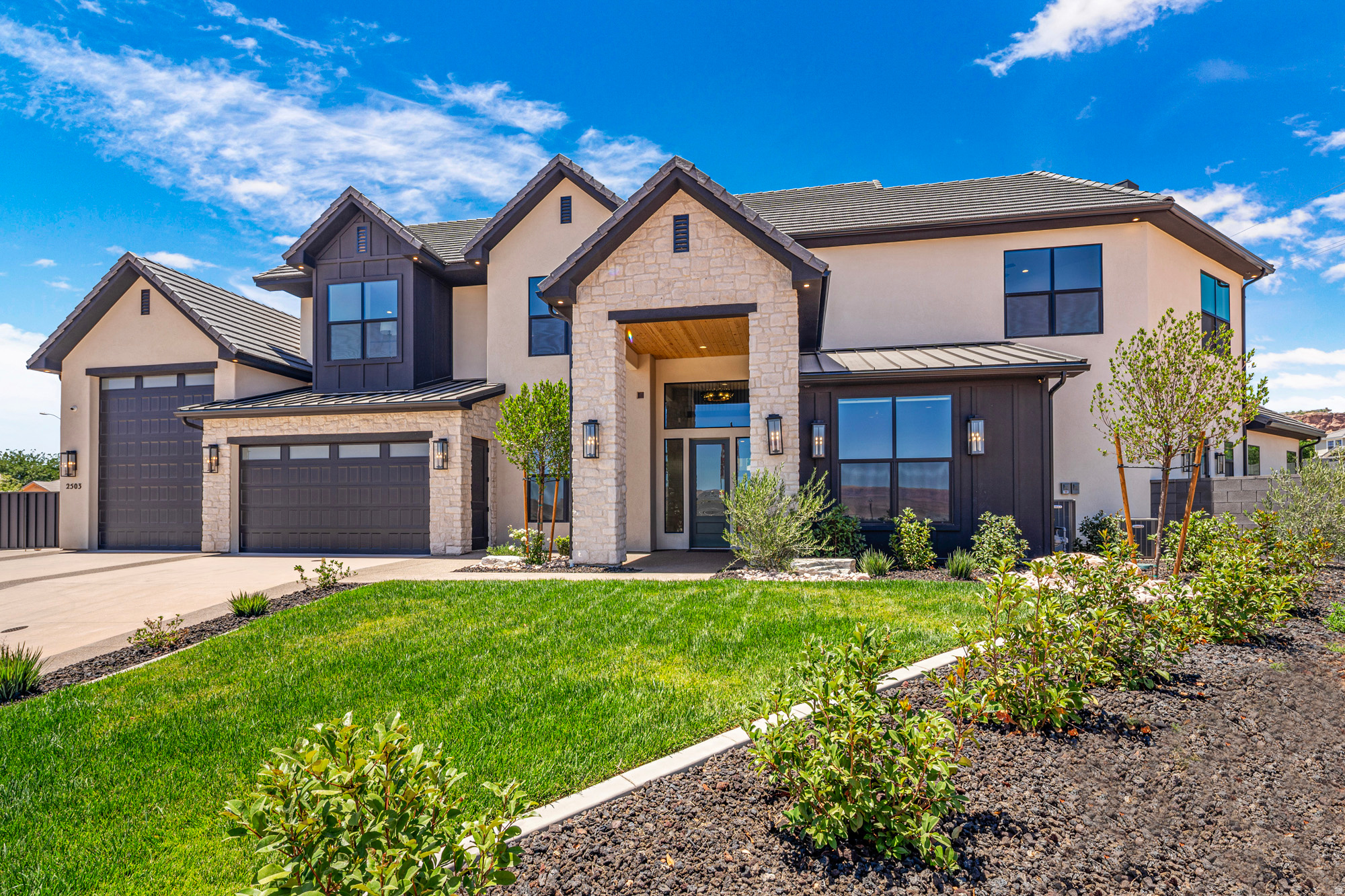 Contemporary stucco and stone exterior featuring multiple gables