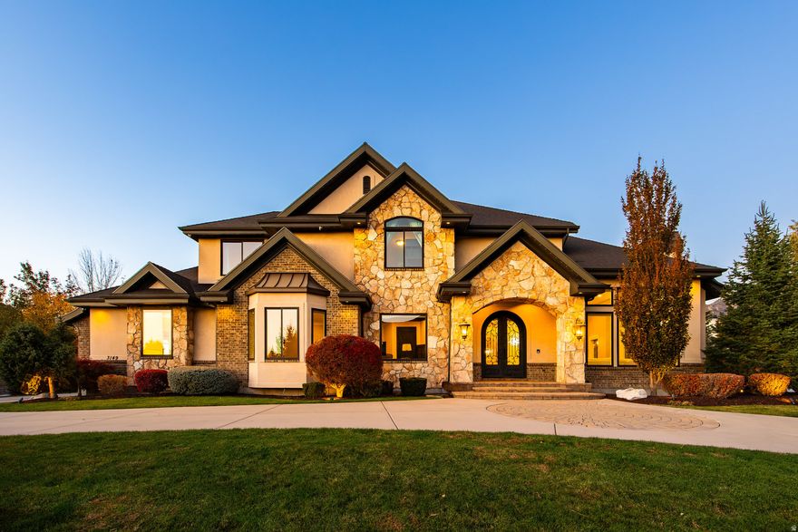 Situated between the breathtaking Wasatch Mountains and the unparalleled convenience of Salt Lake City, this remarkable Sandy estate stands as one of the finest properties ever introduced to the market. Old World sophistication meets modern luxury in this meticulously crafted 7,500 sq. ft. residence, offering six bedrooms and four-and-a-half bathrooms on a pristine half-acre lot. Recently enhanced with a newly installed private gate, new luxury carpet, and custom window coverings, the home now offers an even greater sense of exclusivity, comfort, and refinement. From the moment you arrive, the dramatic twenty-foot entryway with wrought-iron doors, a grand chandelier, and a sweeping staircase sets the tone for the home's exceptional design. Fifteen-foot ceilings in the living and dining rooms, ten-foot ceilings throughout the main level, and expansive panoramic windows frame majestic mountain views. Additional features include an executive-level office, a central vacuum system, energy-efficient lighting, and a Savant Smart Home Alarm System with every door and window fully secured. The residence showcases exquisite craftsmanship with custom woodwork, Italian Travertine flooring, walnut hardwood, two fireplaces with hand-carved stone mantels, tailored Roman shades and draperies, built-in cabinetry, and integrated speakers throughout the main and lower levels-providing an ideal environment for world-class entertaining. The gourmet kitchen serves as the heart of the home and is appointed with Thermador appliances, including a custom wood-paneled refrigerator, four ovens, a six-burner gas range with hood, two spacious islands, granite countertops, and a generously sized walk-in pantry. A formal dining room with its own fireplace enhances the space for memorable gatherings. Designed with an exceptional separation of space, the private main-level primary suite features a tranquil sitting area and an expansive walk-in closet with custom built-ins. The spa-inspired primary bath includes an oversized soaking tub, dual vanities, and a tiled walk-in steam shower - an indulgent retreat for relaxation and rejuvenation. Four additional bedrooms and accompanying baths create the perfect setting for family living or hosting guests. The lower level boasts nine-foot ceilings, limestone accent walls, surround-sound speakers, a 500-bottle temperature-controlled wine cellar, Bosch appliances, and a full secondary kitchen-ideal for entertaining. The impressive home gym offers commercial-grade flooring, an Air King fan, and another steam shower. Outdoors, the estate continues to impress. Impeccable landscaping with mature pine trees, expansive lawn areas, and an oversized patio creates an oasis of privacy and natural beauty. The exterior is enhanced by smart lighting, a welcoming firepit, a commercial-grade gas grill with rotisserie, and a Chicago brick pizza oven-perfect for alfresco dining and effortless entertaining. A radon mitigation system further enhances the home's safety. Perfectly positioned minutes from world-renowned ski resorts, Dimple Dell Canyon, scenic trails, and sweeping mountain views, this residence offers a lifestyle that is both luxurious and deeply connected to the outdoors. Recognized as one of Money.com's "Best Places to Live," Sandy is also consistently ranked among the nation's safest cities-making this gated estate even more exceptional.