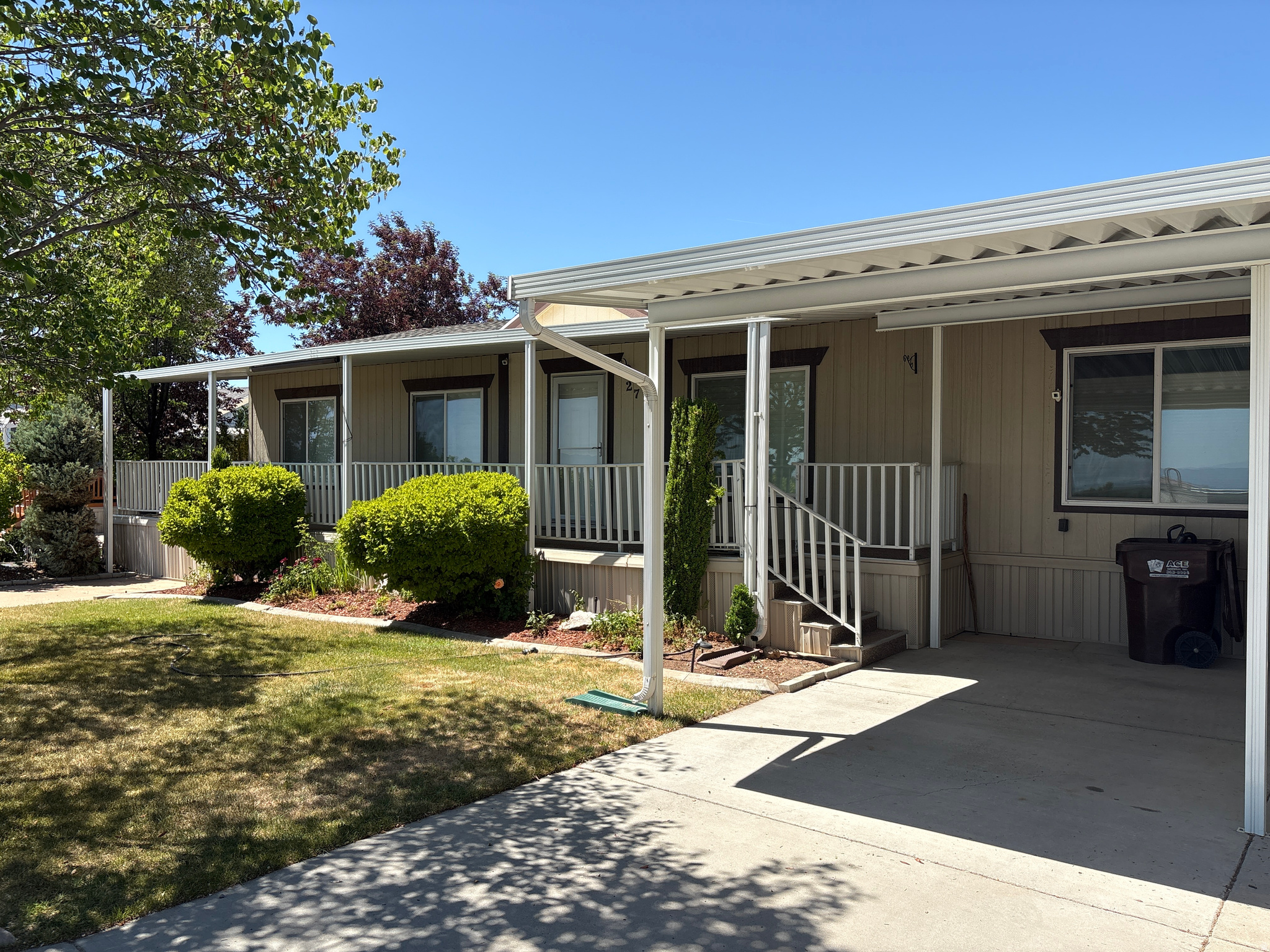 Exterior featuring a covered carport, covered porch with white railings, and a concrete driveway