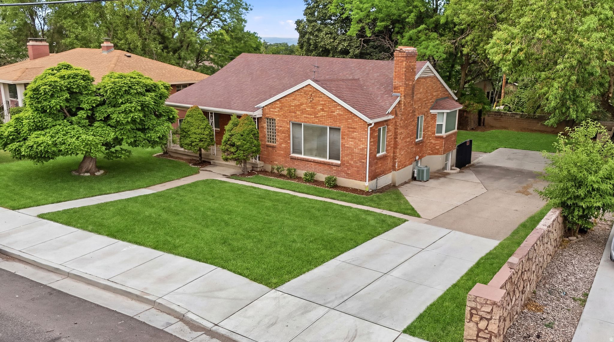Brick exterior residence featuring a front lawn and mature landscaping