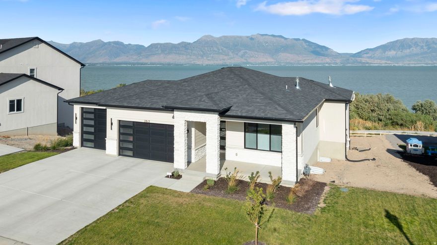 RARE UTAH LAKEFRONT LUXURY. Thoughtfully designed as a high-end rambler, this home delivers elegant main-level living with comfort, accessibility, and timeless style. Extensive custom upgrades throughout reflect a no-expense-spared approach to quality.  Outdoor living is extraordinary. Expansive, professionally designed decks frame unobstructed lake and mountain views with no backyard neighbors. A modern spiral staircase connects multiple spaces for entertaining or relaxing, while the backyard offers a rare blank canvas for a custom outdoor sanctuary-ideal for refined landscaping or outdoor entertaining.  Interior highlights include Cafe white appliances, custom office cabinetry, a basement kitchenette, two fireplaces, and custom built-ins, and striking inside-out black windows that create a clean, modern aesthetic. The primary suite showcases stunning lake and mountain views, a spa-inspired bath with a separate tub and shower, and a fully customized walk-in closet. Additional features include modern top-down, bottom-up window coverings, premium water softening and filtered drinking water systems on both floors, a finished garage with epoxy flooring and EV-charging, and exterior conveniences such as an outdoor BBQ gas line and hot tub outlet.  Move in now and enjoy lakefront living from day one. Opportunities like this are limited, making it an exceptional option for buyers seeking a true waterfront lifestyle. A fully furnished option is available at the right price, and special mortgage savings may be offered to qualified buyers.