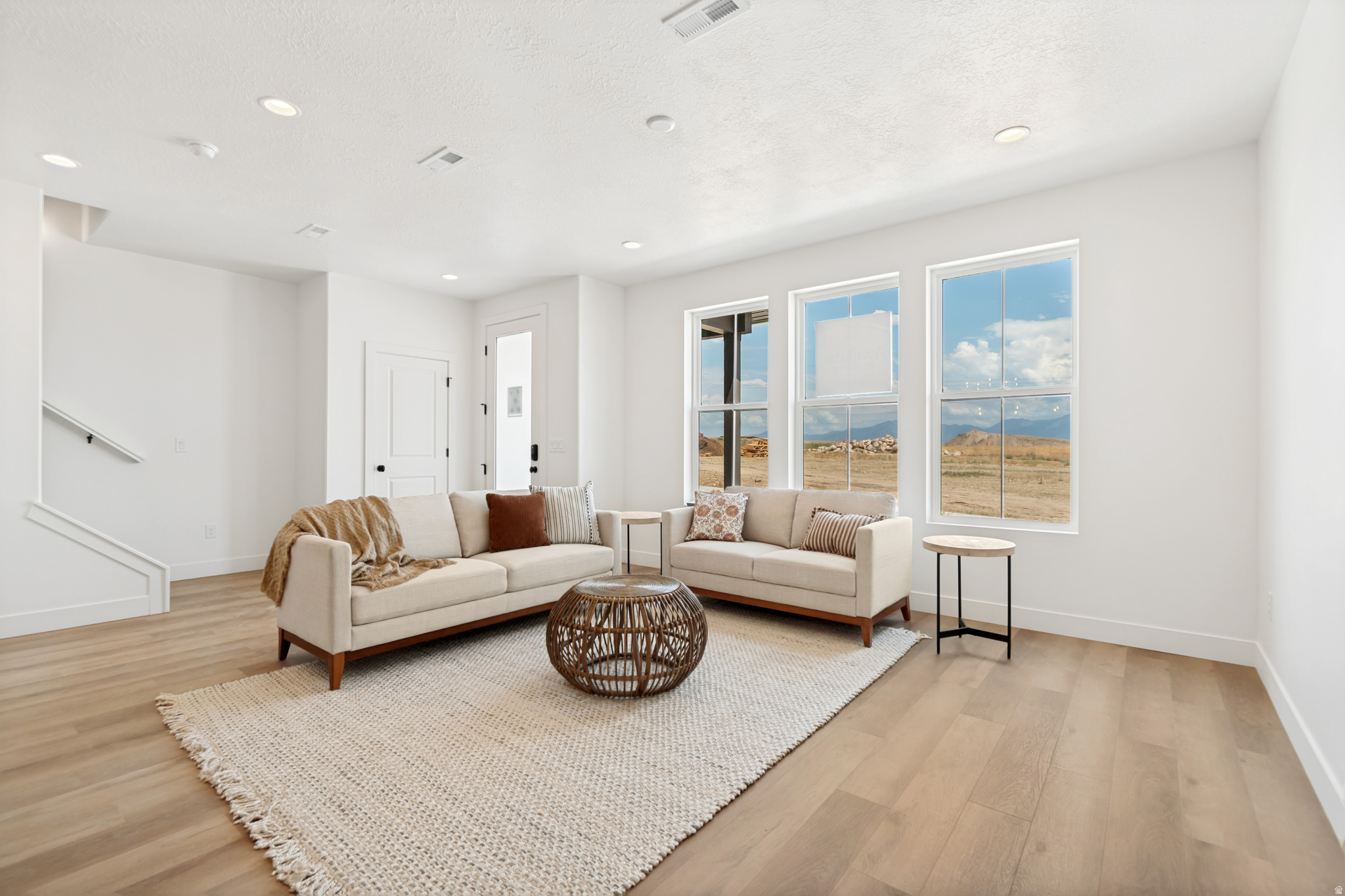 Bright living area featuring abundant natural light, recessed lighting, wood-finish flooring, and white walls
